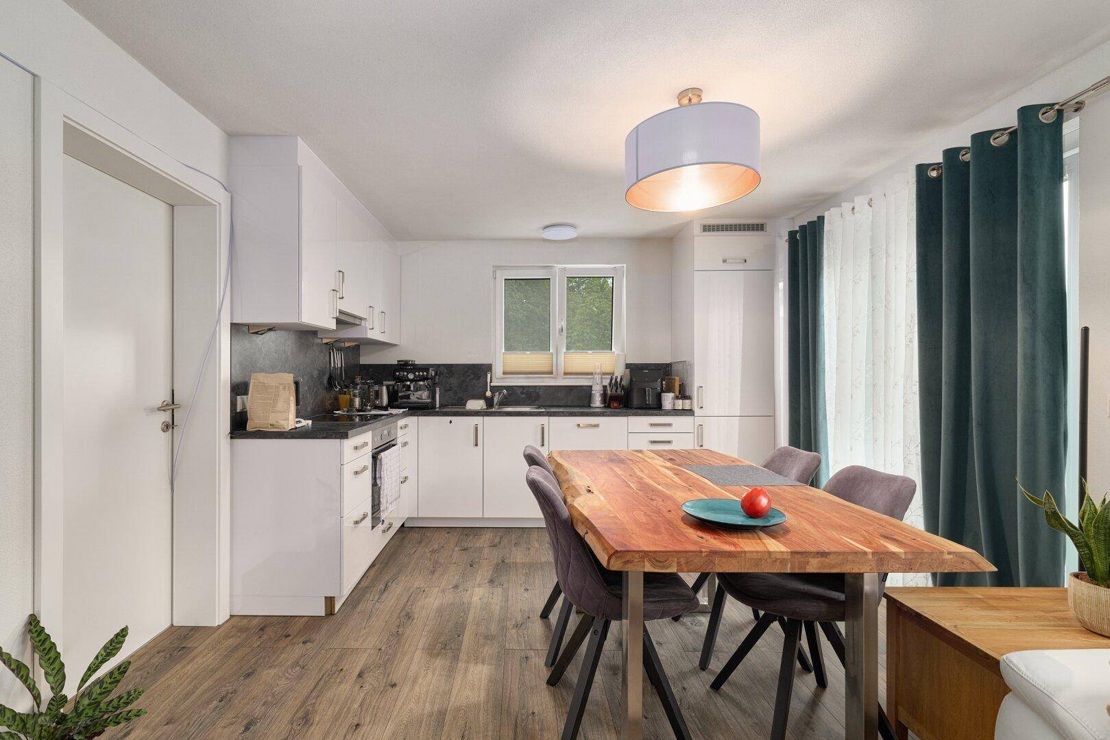 Moderne Einbauküche mit Holztisch und Essbereich, ausgestattet mit zeitgemäßen Geräten und Vorhängen.