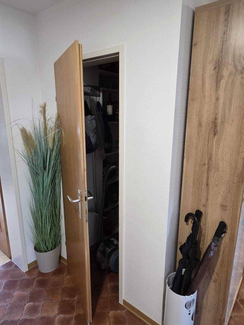 Flur mit Fliesenboden, einer Pflanze und einem offenen Abstellraum für zusätzlichen Stauraum.