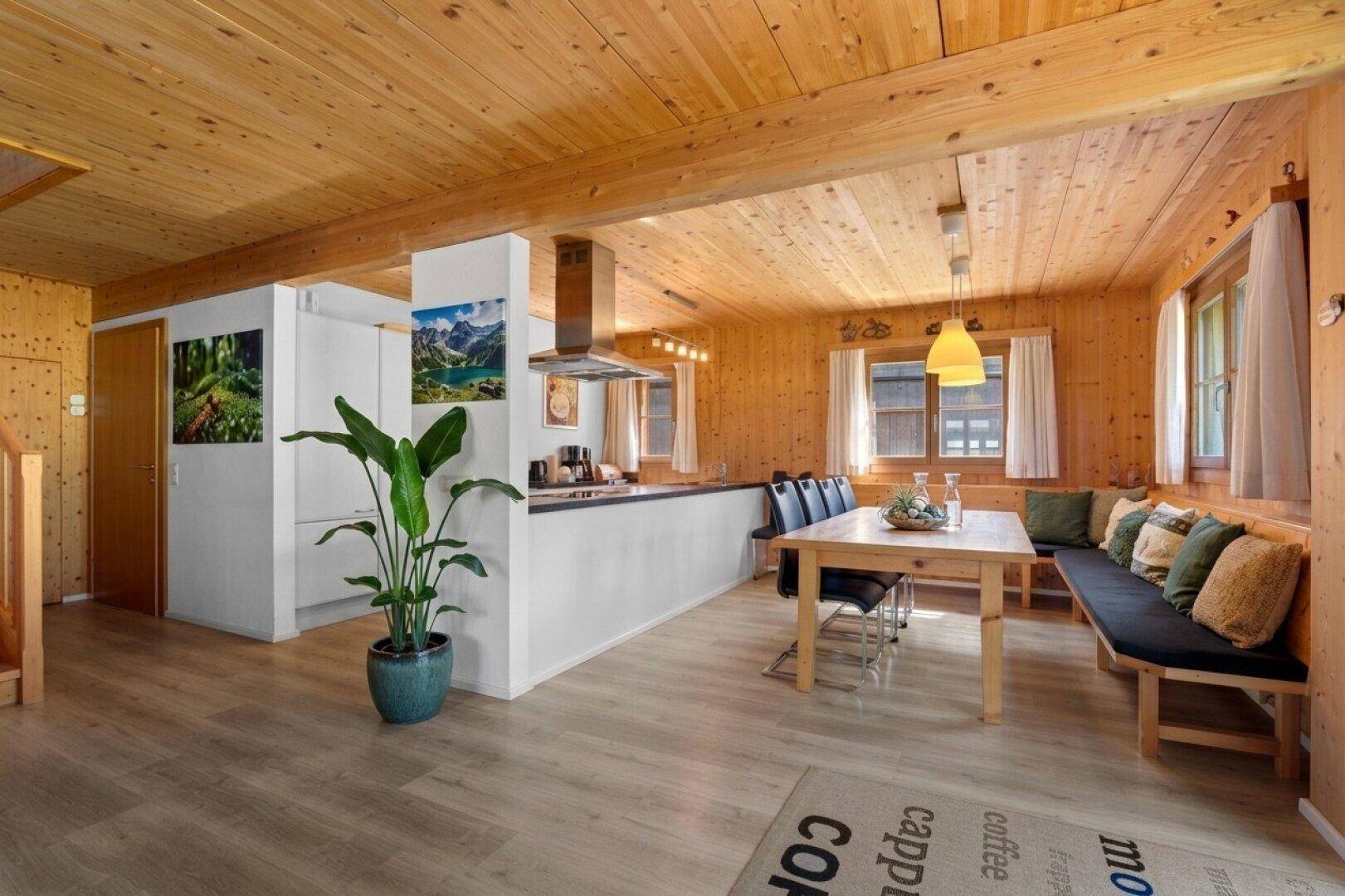 Gemütlicher Wohn-Essbereich mit Holzwänden, offener Küche und Essbereich mit Sitzbank.