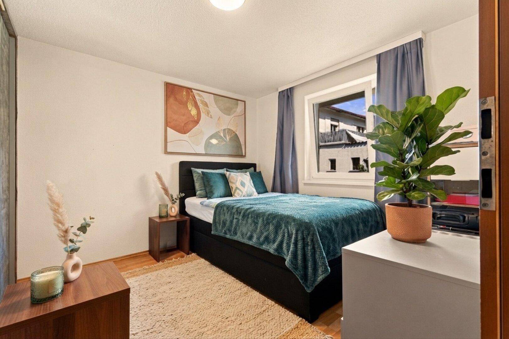 Ruhiges Schlafzimmer mit Einzelbett, Holzboden und einem Fenster mit Blick ins Grüne.