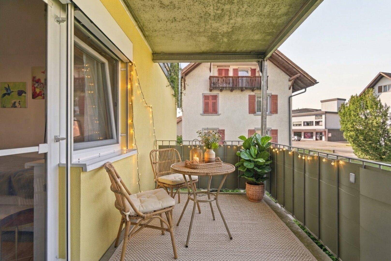 Gemütlicher Balkon mit Sitzgelegenheiten, Dekoration und Lichterkette für entspannte Abende im Freien.