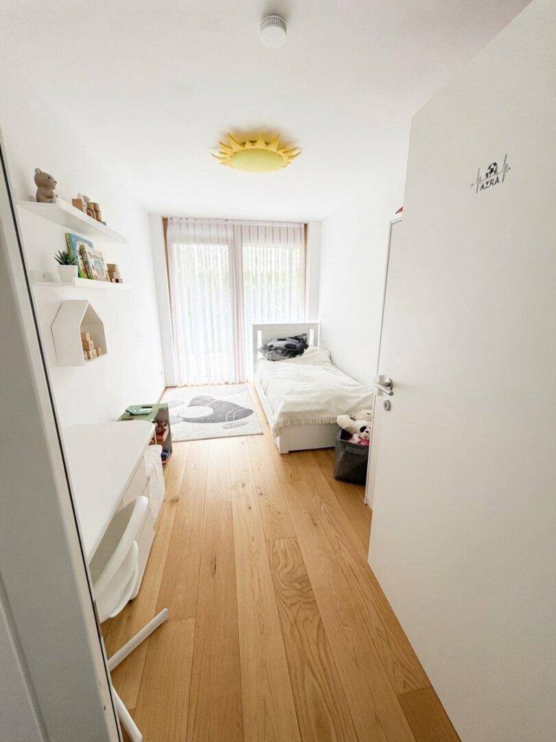Helles Kinderzimmer mit Einzelbett, Schreibtisch und spielerischer Sonnenlampe an der Decke.