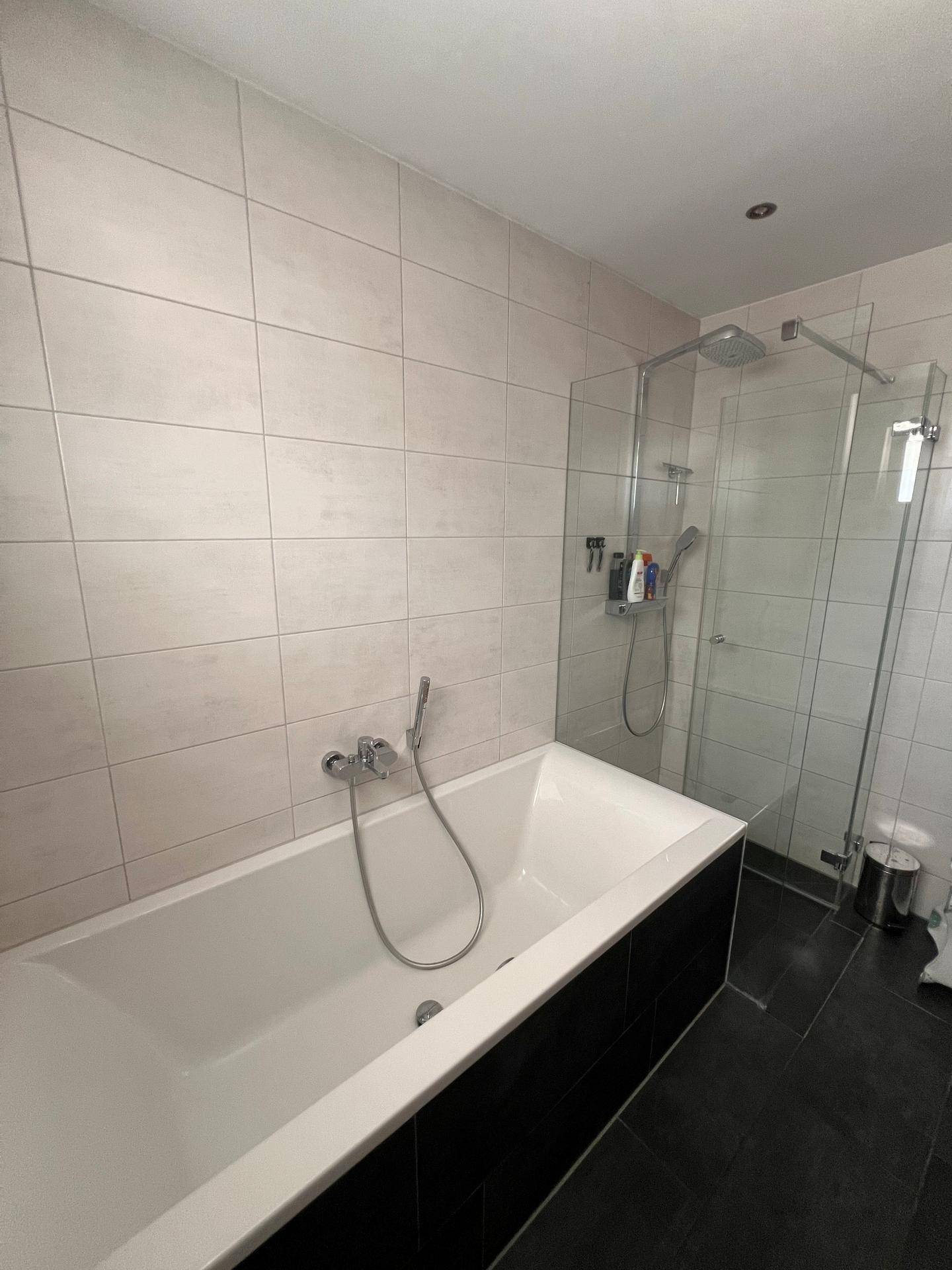 Badezimmer mit Badewanne und moderner begehbarer Dusche mit Glasabtrennung.