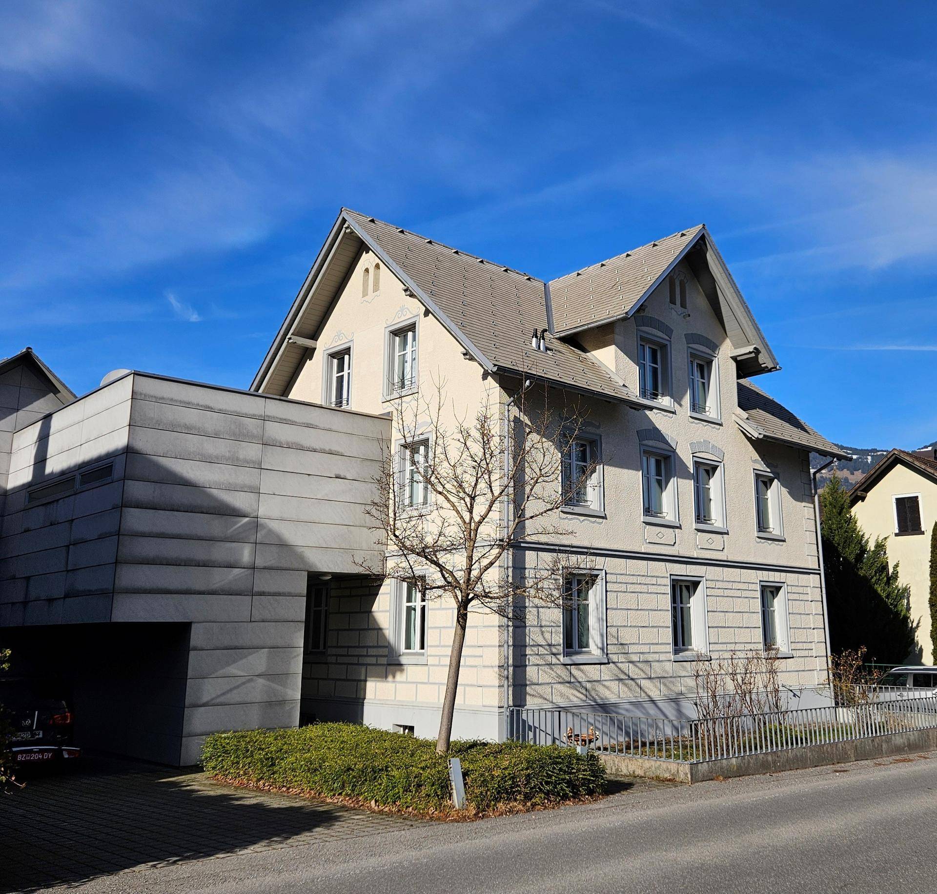 Ansicht des Gebäudes mit traditioneller Architektur und einem modernen, kubischen Anbau.