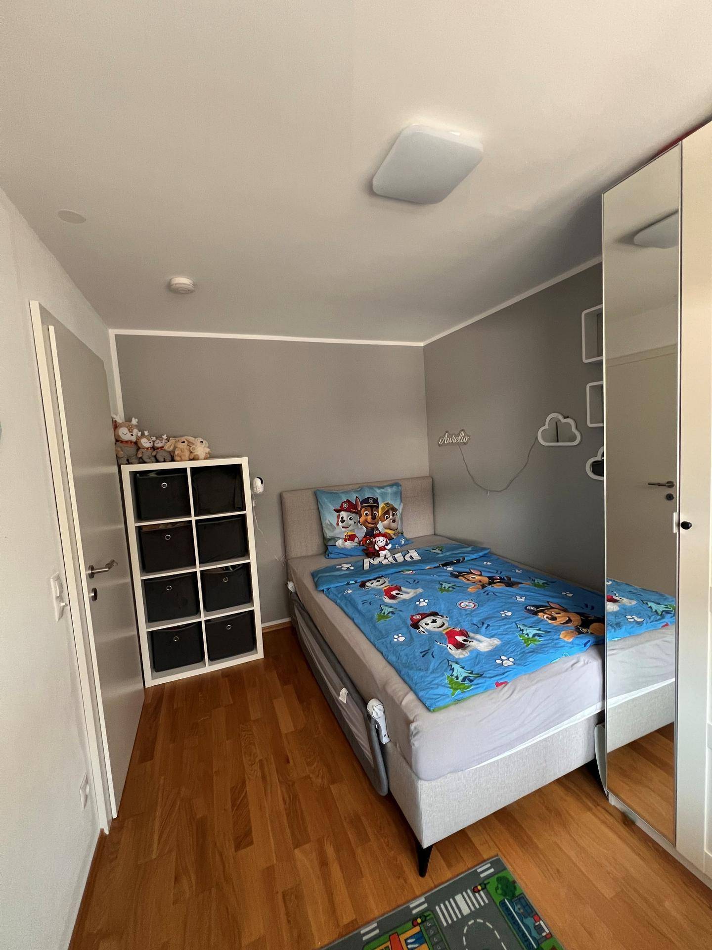 Kinderzimmer mit Einzelbett, Stauraum und hellem Holzboden.