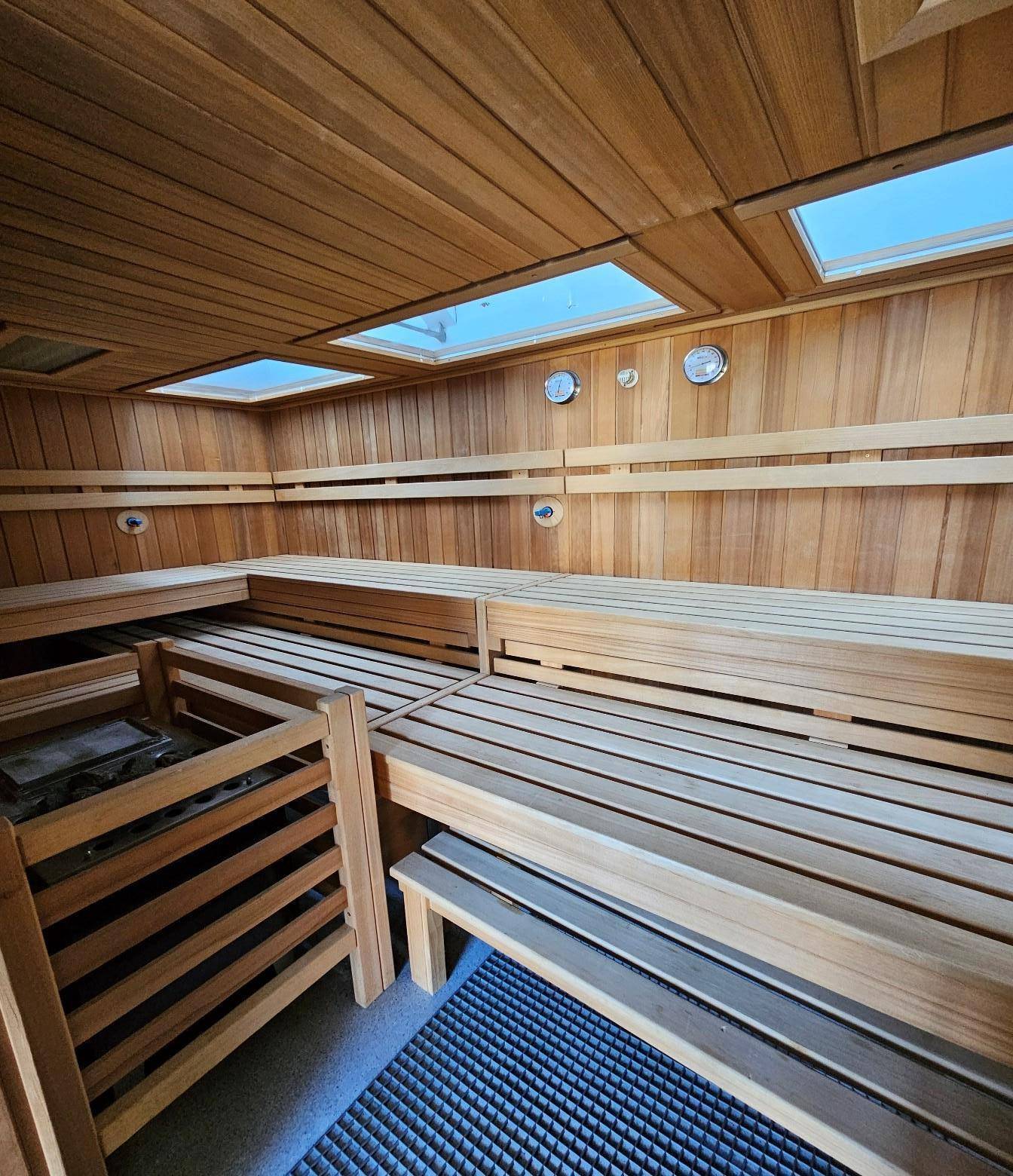 Geräumige Holzsauna mit mehreren Bänken und Oberlichtern für entspannende Wellnessmomente.