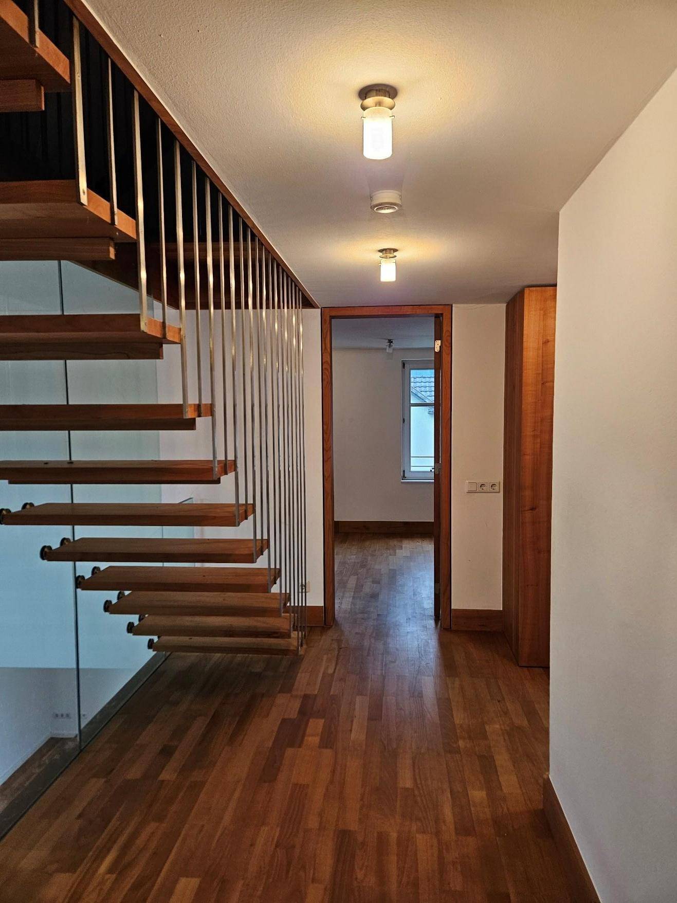 Heller Flur mit Holztreppe und Holzboden, führt zu weiteren Räumen.