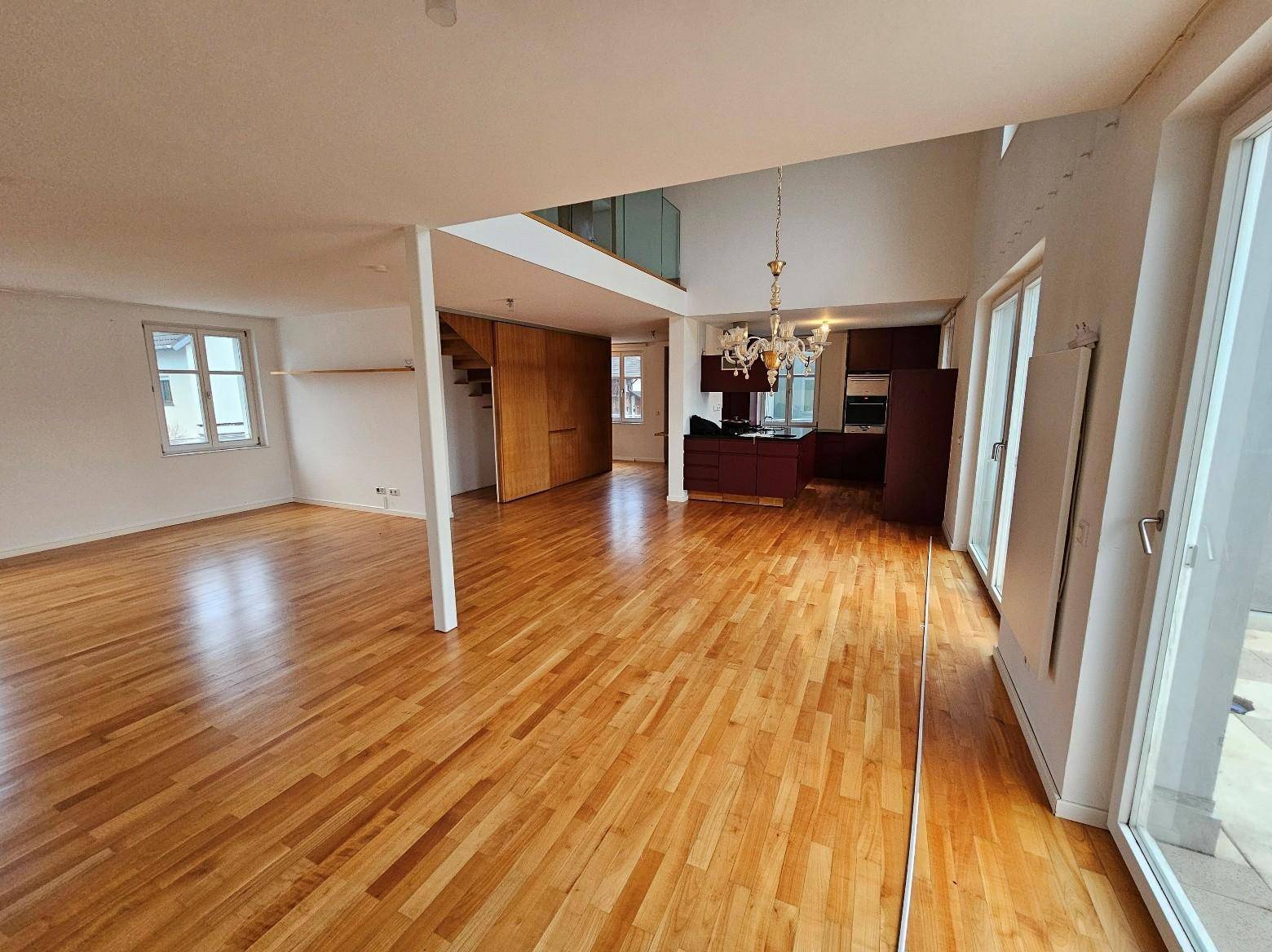Geräumiger offener Wohn-Essbereich mit Holzboden, hohen Decken und Zugang zur Terrasse.