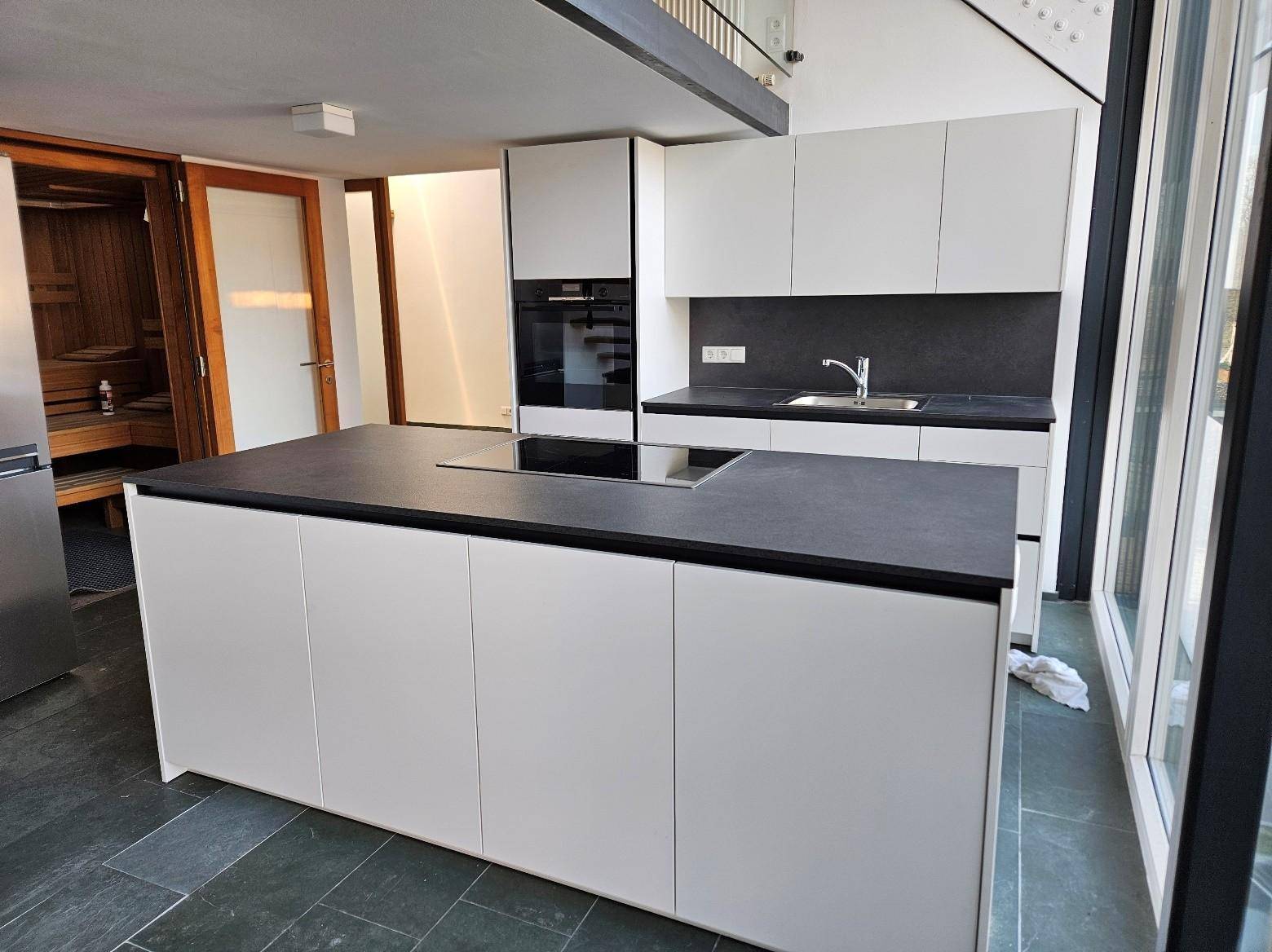 Detailansicht der modernen Küche mit Kochinsel, Induktionskochfeld und integriertem Backofen.