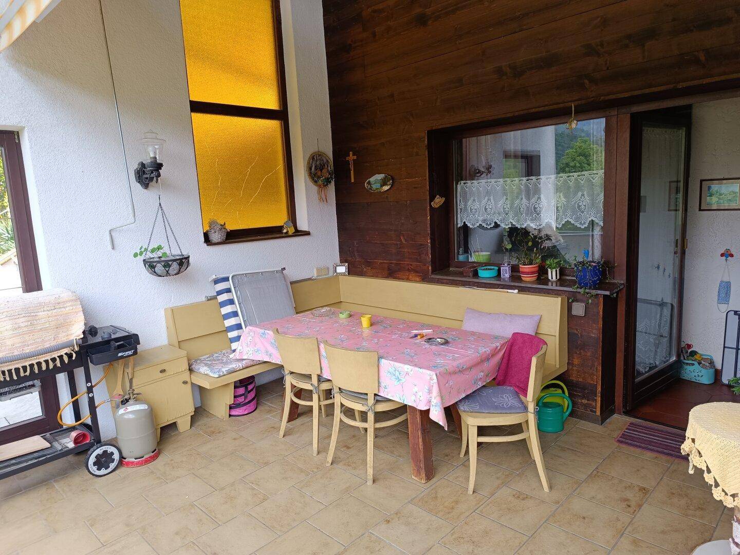 Überdachter Essbereich im Freien mit Holzwänden, Esstisch und Grill, ideal für gesellige Stunden.