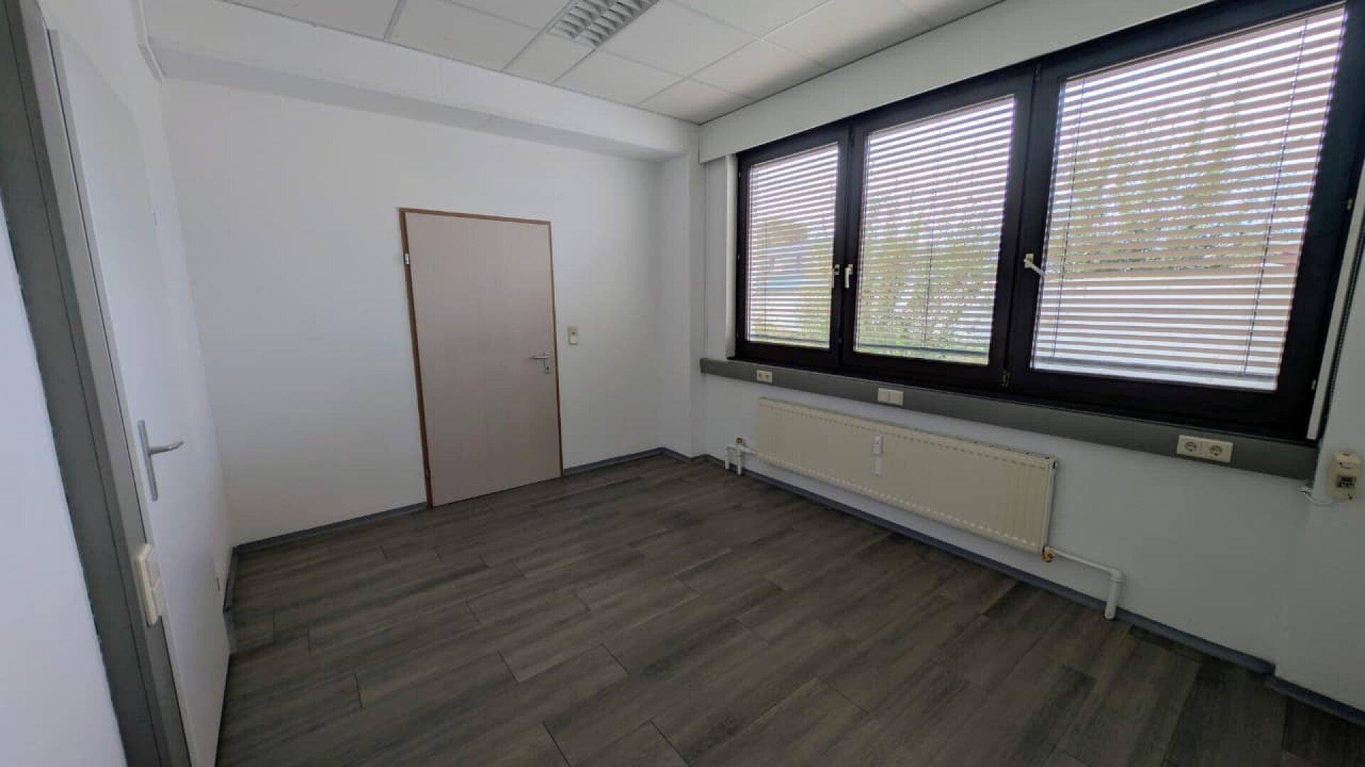 Helles Büro mit hellem Boden, weißen Wänden und Fenster mit Jalousien, schafft eine angenehme Arbeitsatmosphäre.