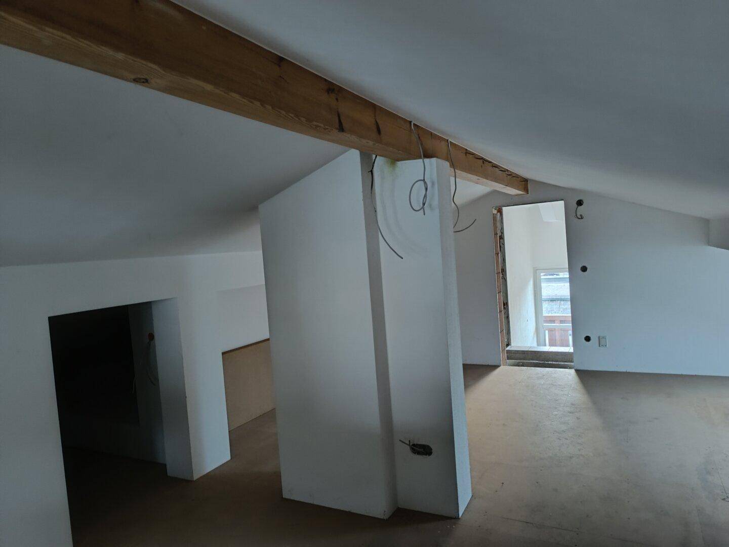 Geräumiges Dachgeschoss mit sichtbarem Holzbalken und offenem Grundriss, bereit zum Ausbau.