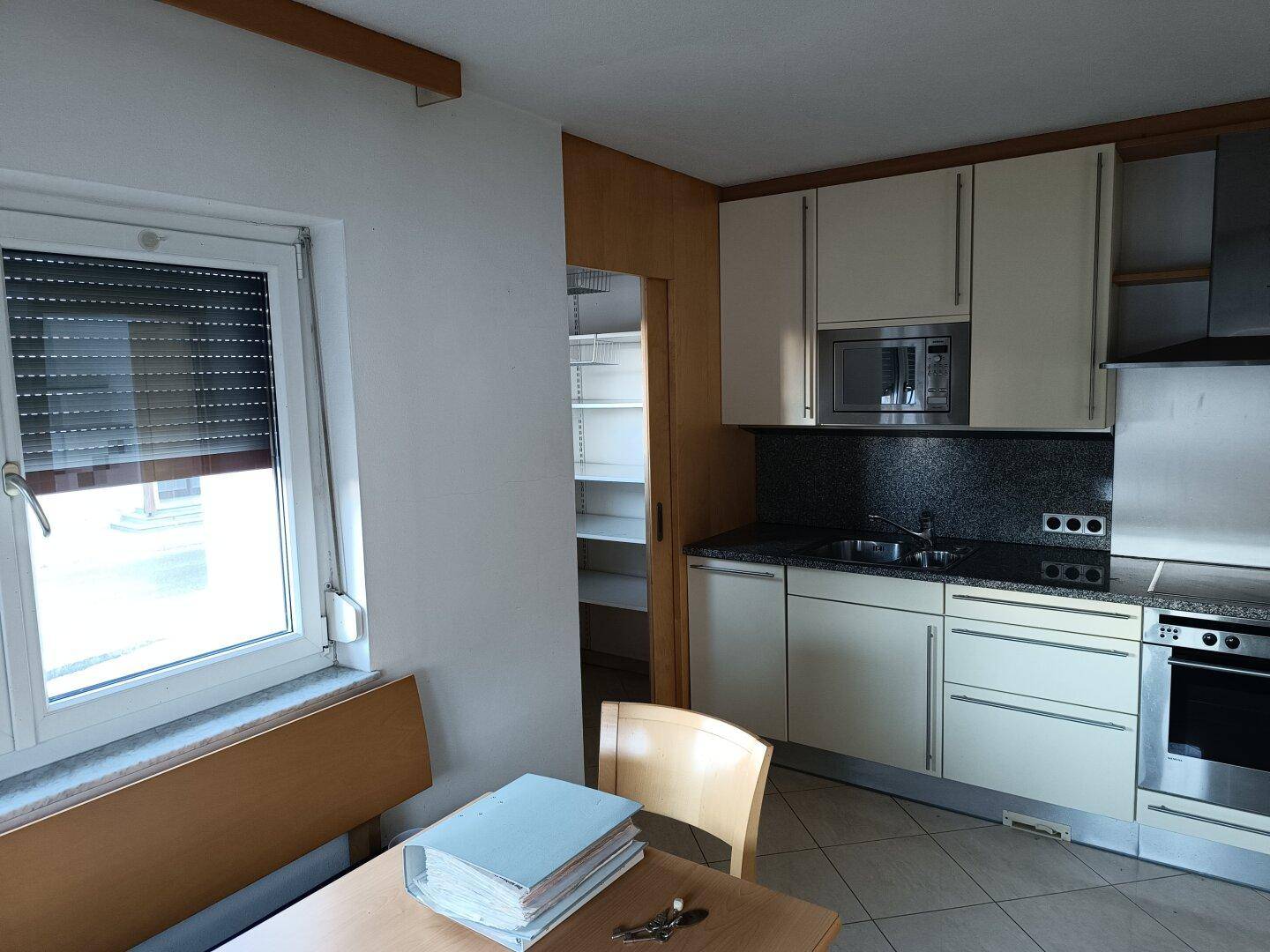 Funktionale Küche mit hellen Einbauschränken, integrierten Geräten und einem Essbereich.