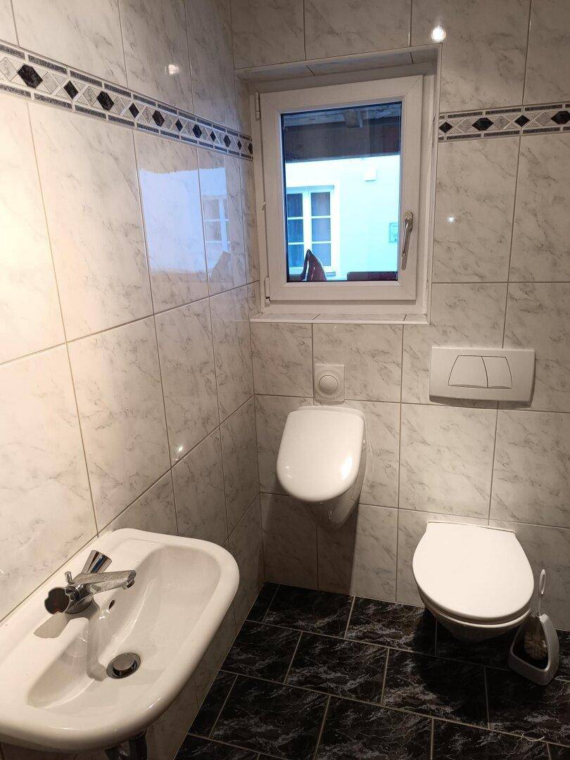 Modern gefliestes Badezimmer mit Bidet, Urinal und wandhängendem WC.