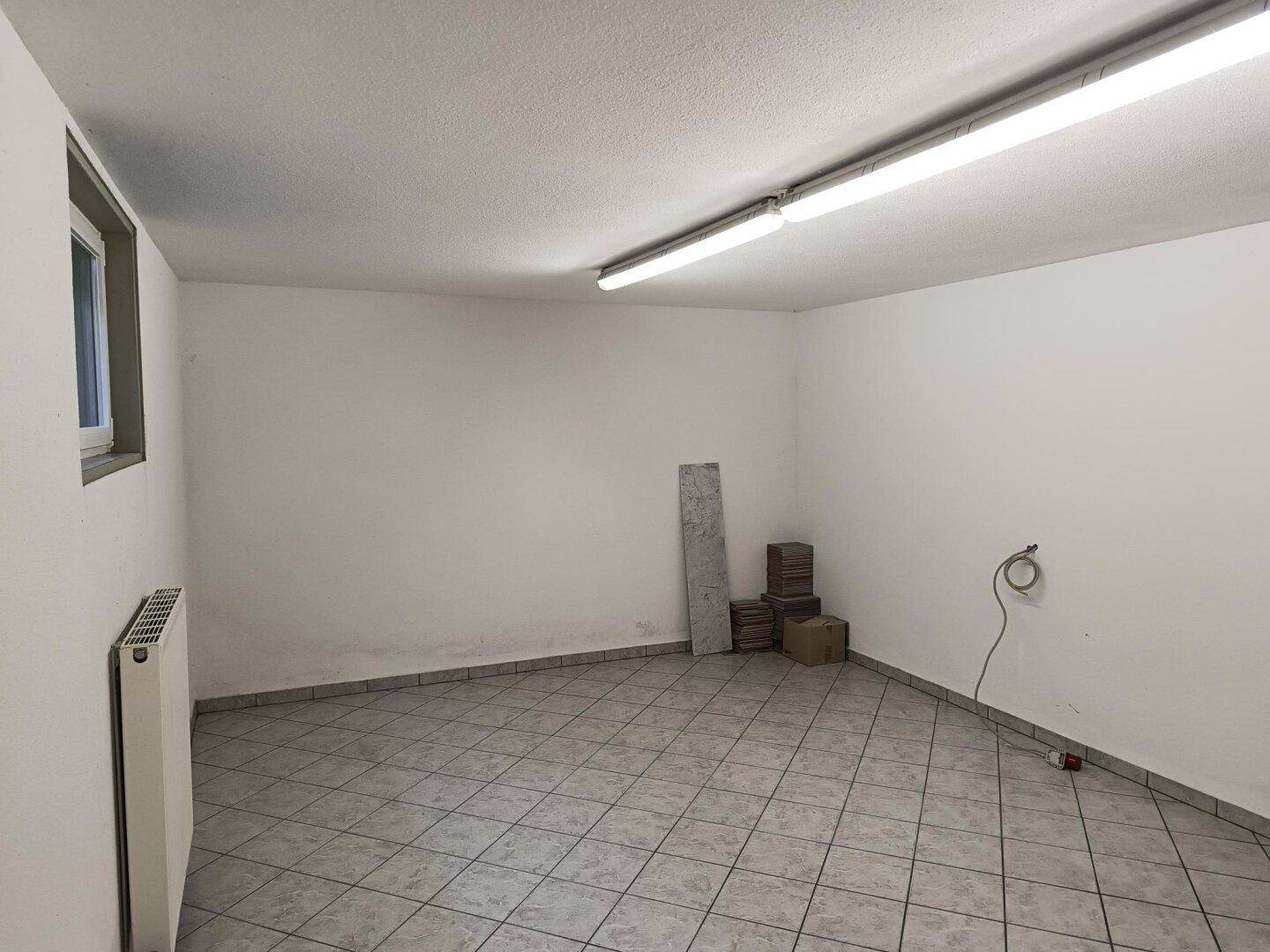 Heller Raum mit Fliesenboden, Fenster und Heizkörper, ideal als Abstell- oder Hobbyraum.
