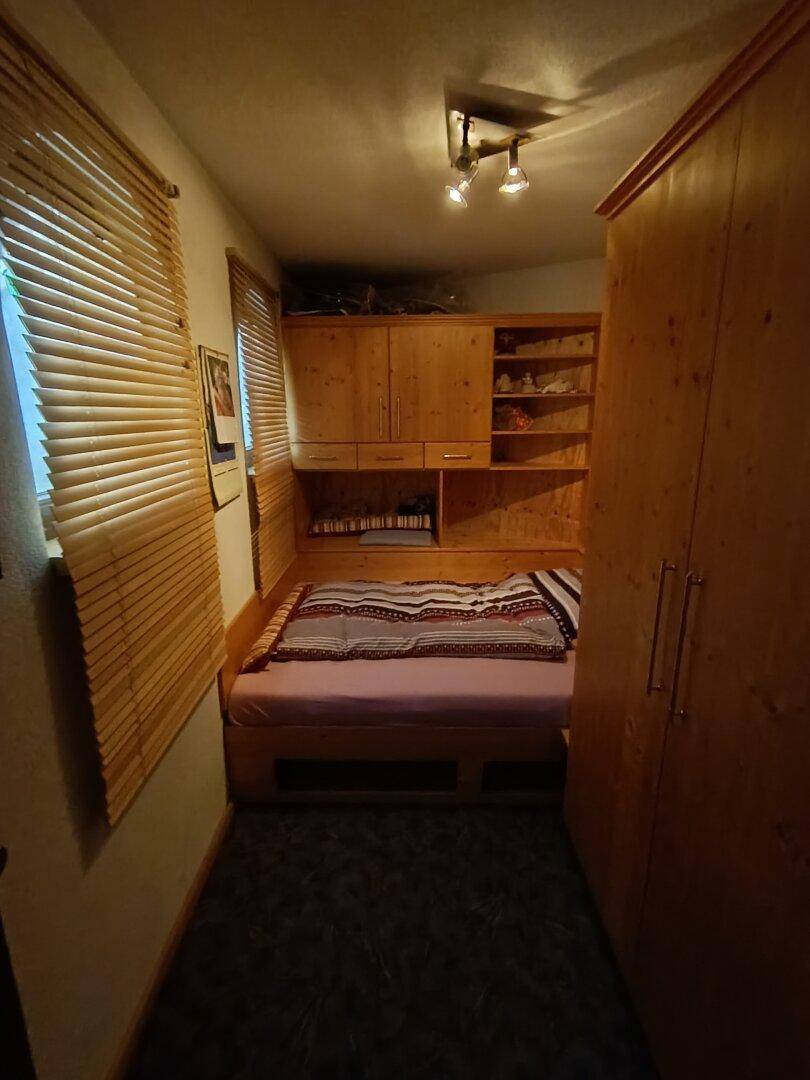 Gemütliches Schlafzimmer mit eingebautem Holzbett und Schränken, bietet eine warme Atmosphäre.
