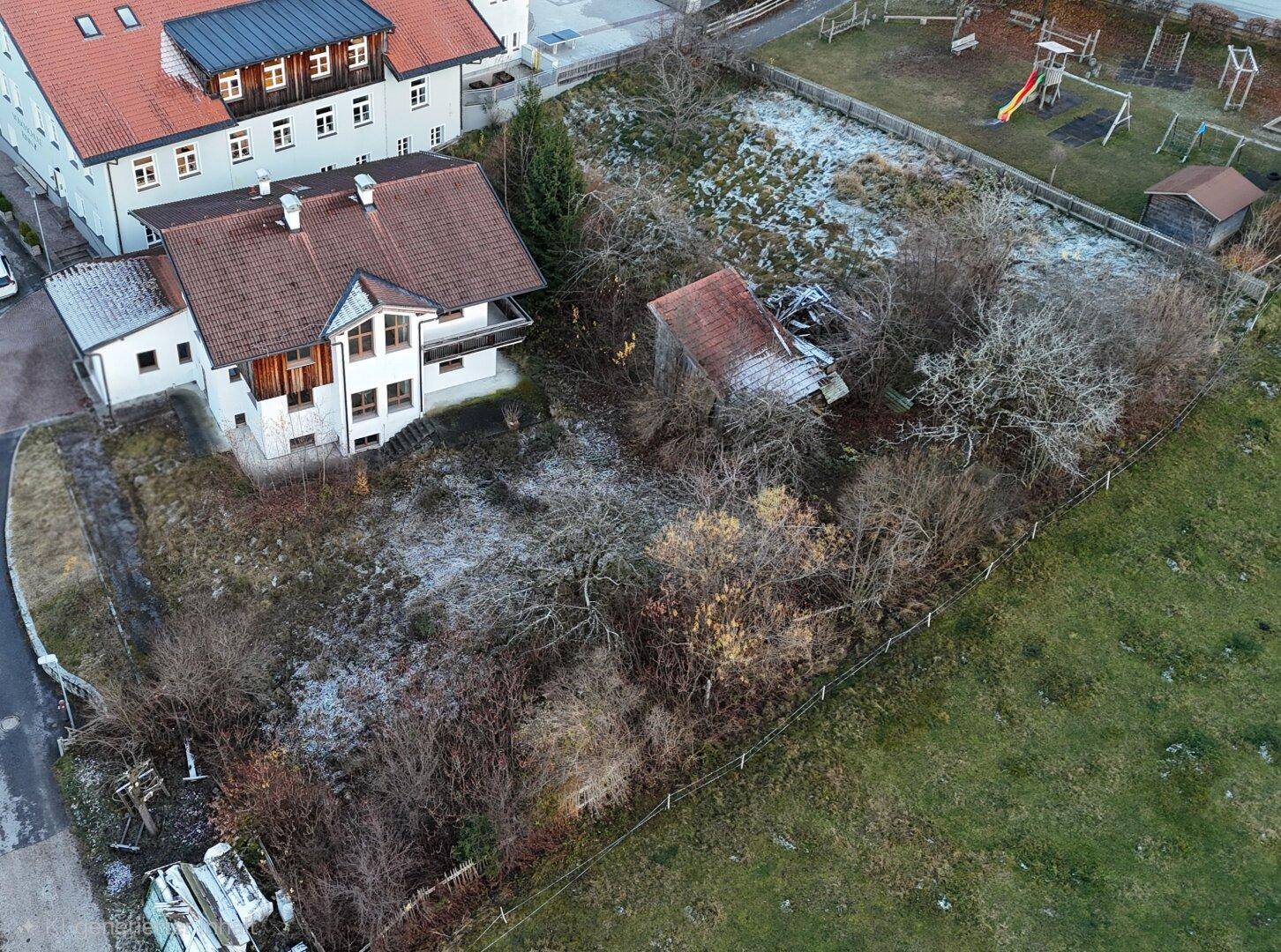 Luftaufnahme eines Wohnhauses mit Nebengebäude und angrenzendem Spielplatz in ländlicher Umgebung.
