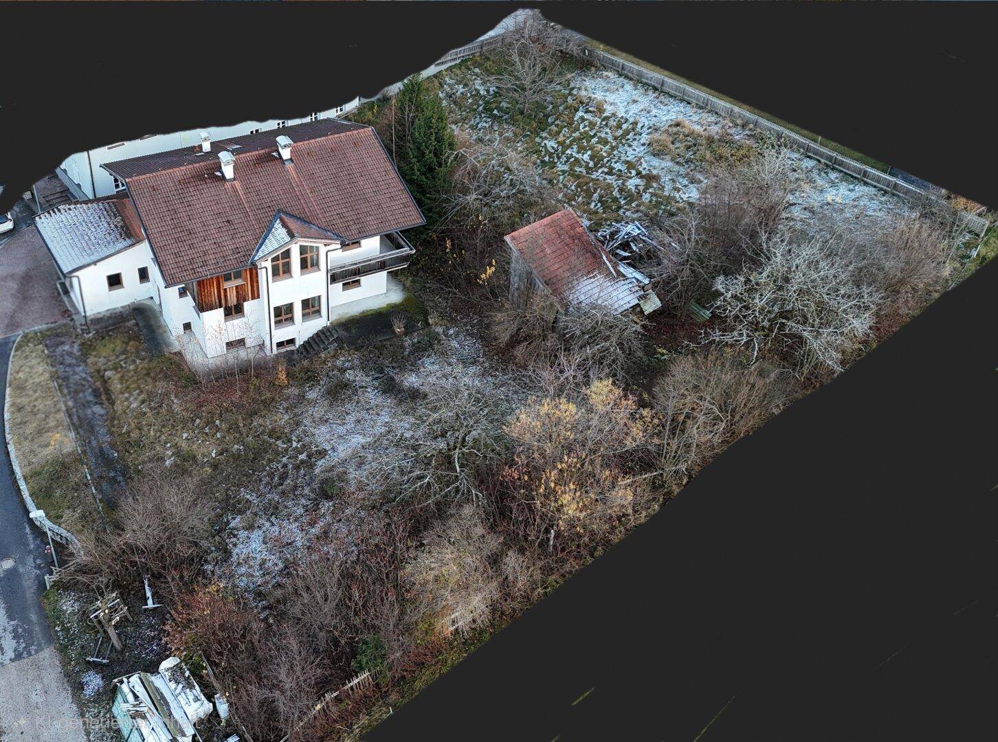 Luftaufnahme eines Anwesens mit Wohnhaus, Nebengebäude und umliegendem Grundstück im Winter.