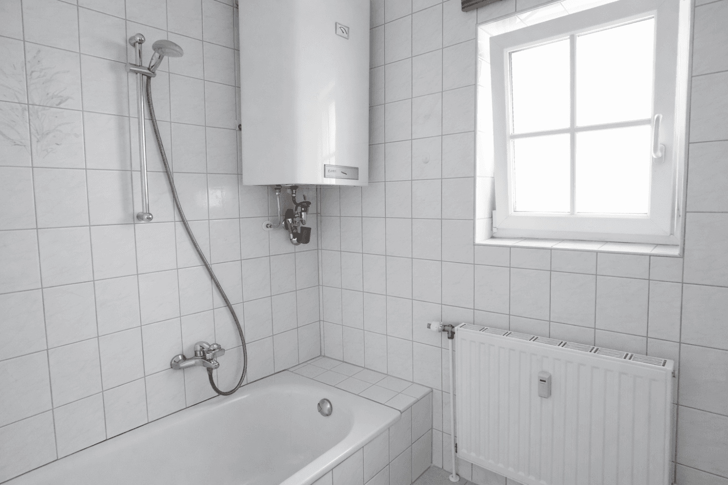 Helles Badezimmer mit weißen Fliesen, Badewanne mit Duschfunktion und einem Fenster für Tageslicht.