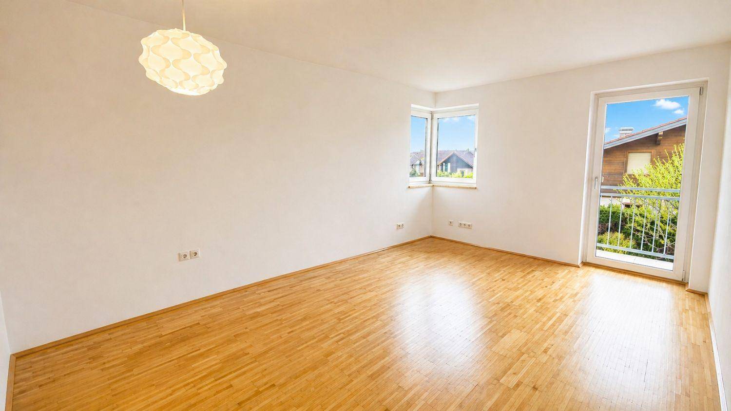 Leerer, heller Raum mit Parkettboden und Zugang zu einem kleinen Balkon, ideal als Schlafzimmer.