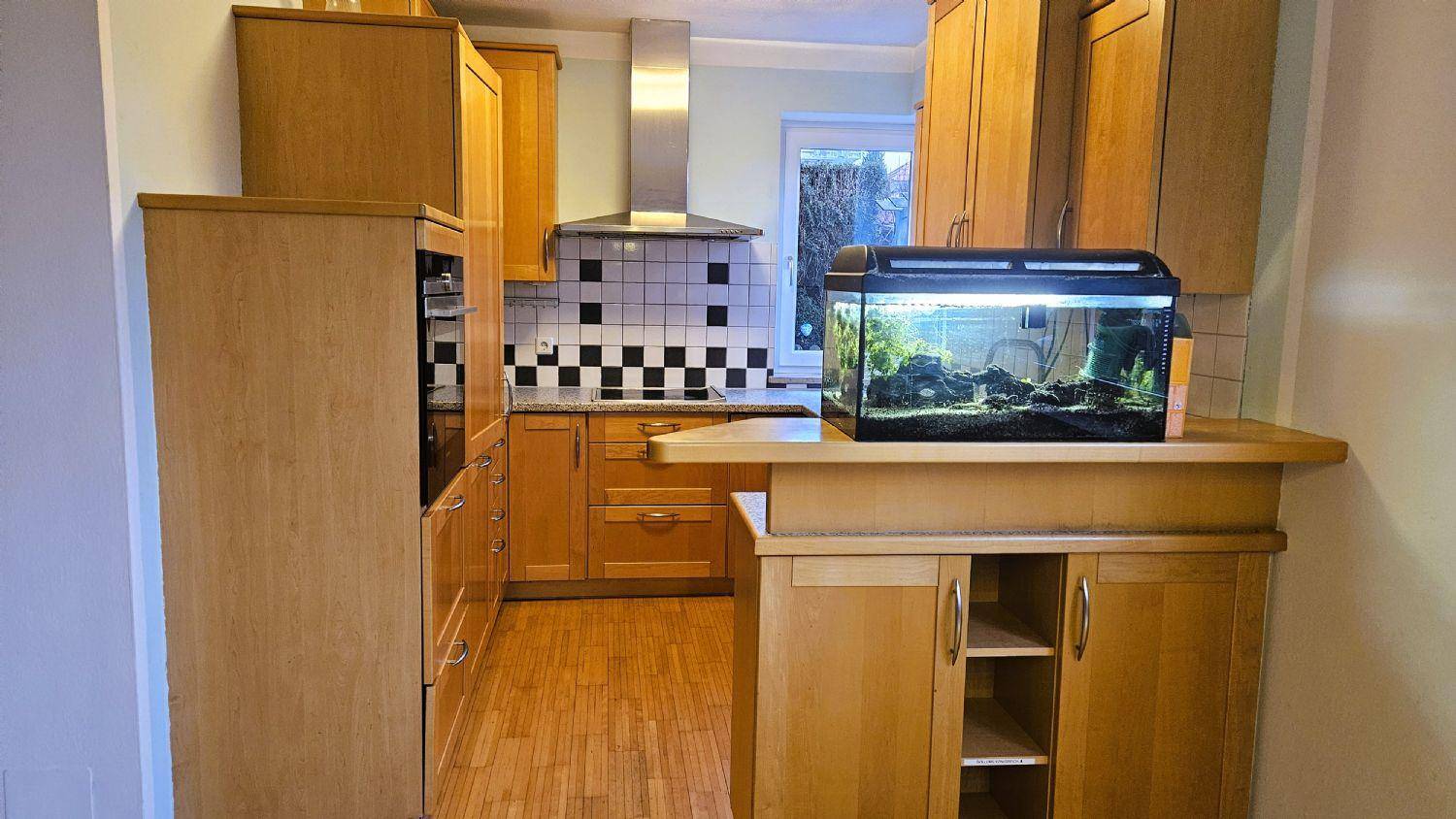 Funktionale Küche mit Holzschränken, Granitarbeitsplatten und einem dekorativen Aquarium.