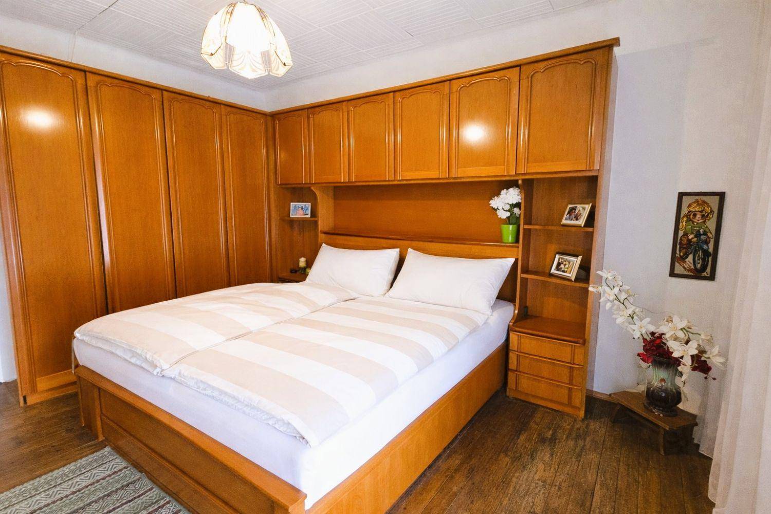 Schlafzimmer mit großem Einbauschrank aus Holz und Doppelbett.