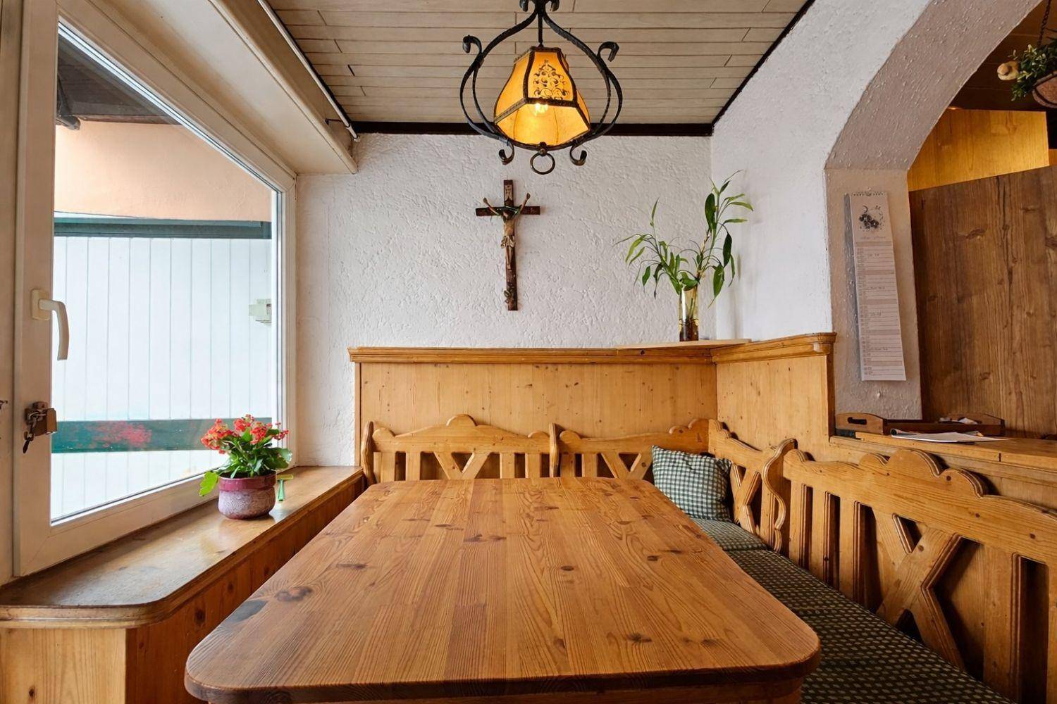 Gemütlicher Essbereich mit traditioneller Eckbank aus Holz und Blick nach draußen.