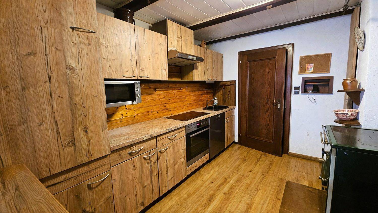 Rustikale Küche mit Holzfronten, integrierten Geräten und traditionellem Holzofen.