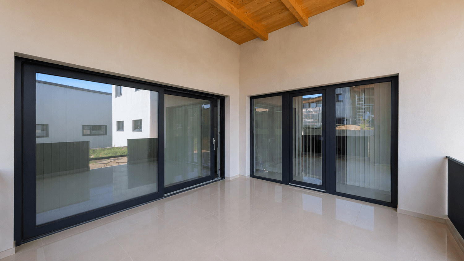 Überdachte Loggia mit großen Glasschiebetüren und einer sichtbaren Holzdecke, die viel Licht hereinlässt.