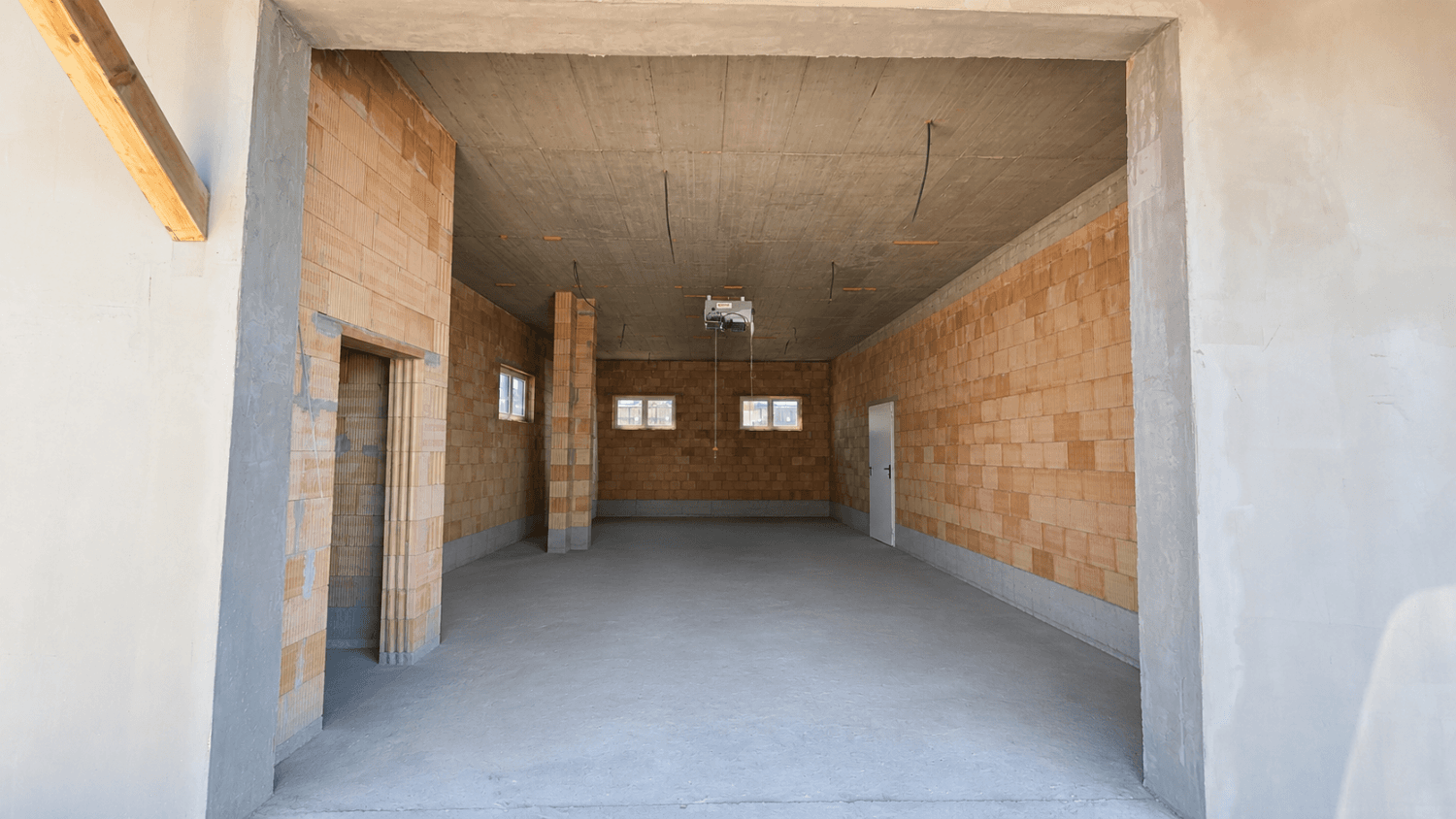 Unfertiger Innenraum mit unverputzten Ziegelwänden, Betonboden und -decke, bereit für den Ausbau.