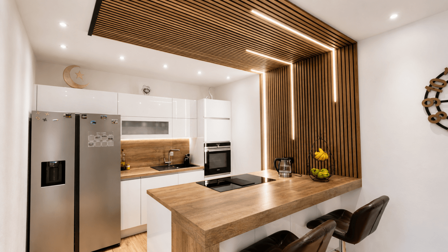 Moderne Küche mit weißen Hochglanzfronten, Holztheke und integrierten Geräten.