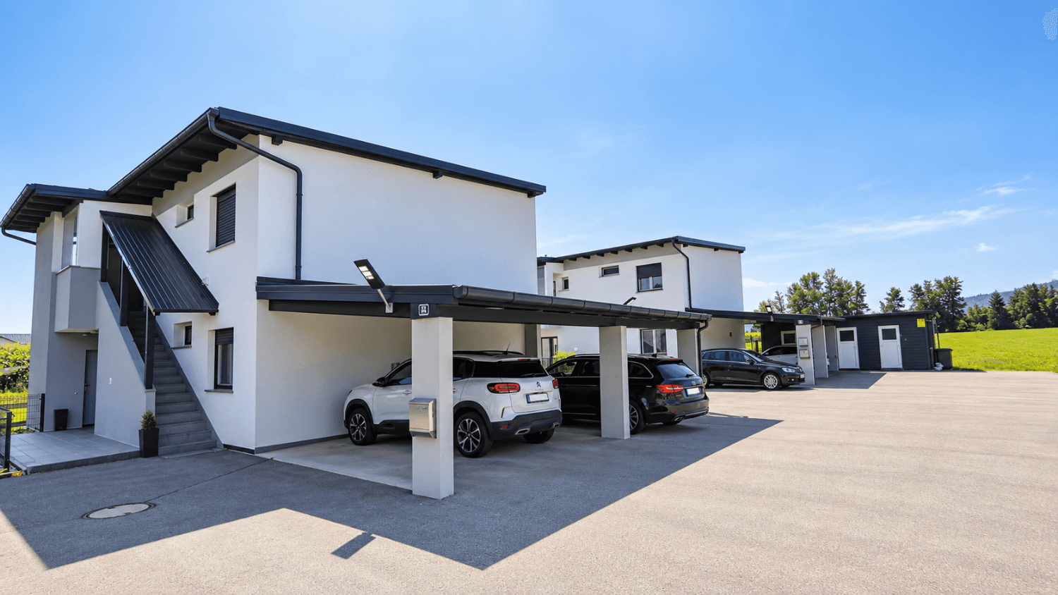 Moderne Reihenhäuser mit Carports und ausreichend Parkmöglichkeiten im Freien.