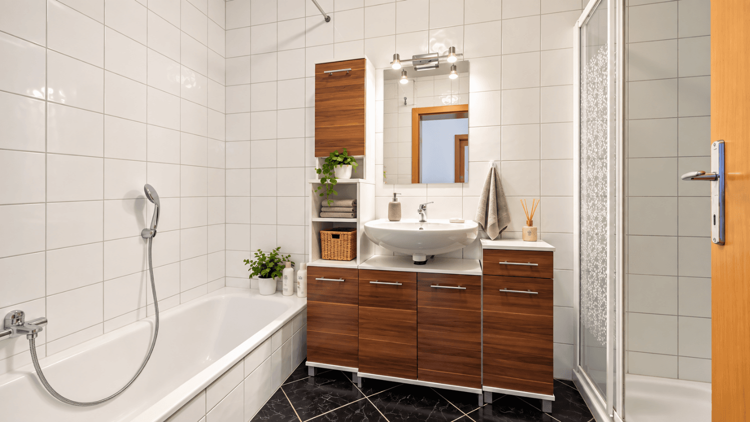 Funktionales Badezimmer mit Badewanne, Dusche, Waschbecken und weißen Wandfliesen.