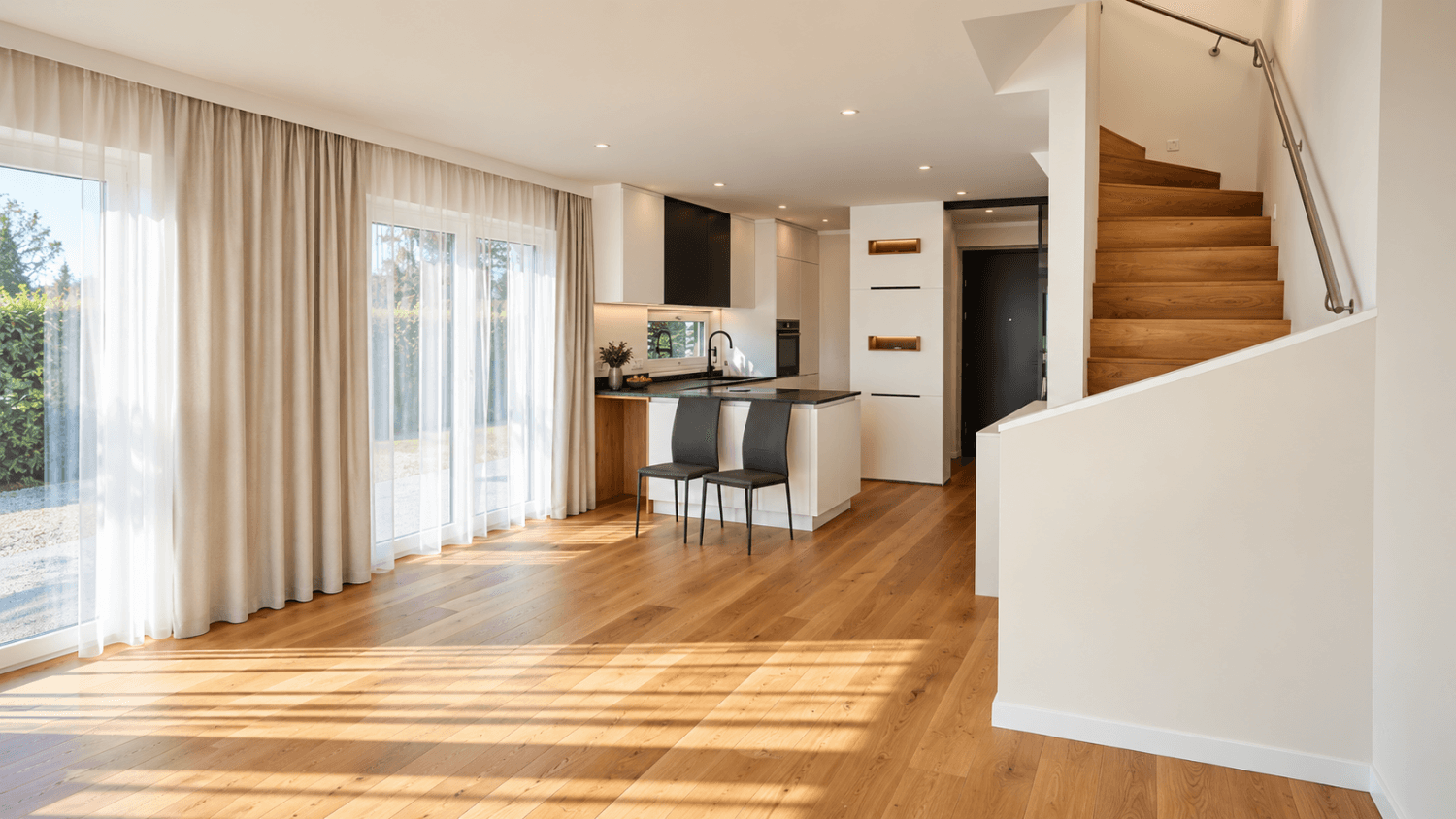 Offener Wohnbereich mit integrierter Küche, Holzboden und Zugang zur Terrasse.