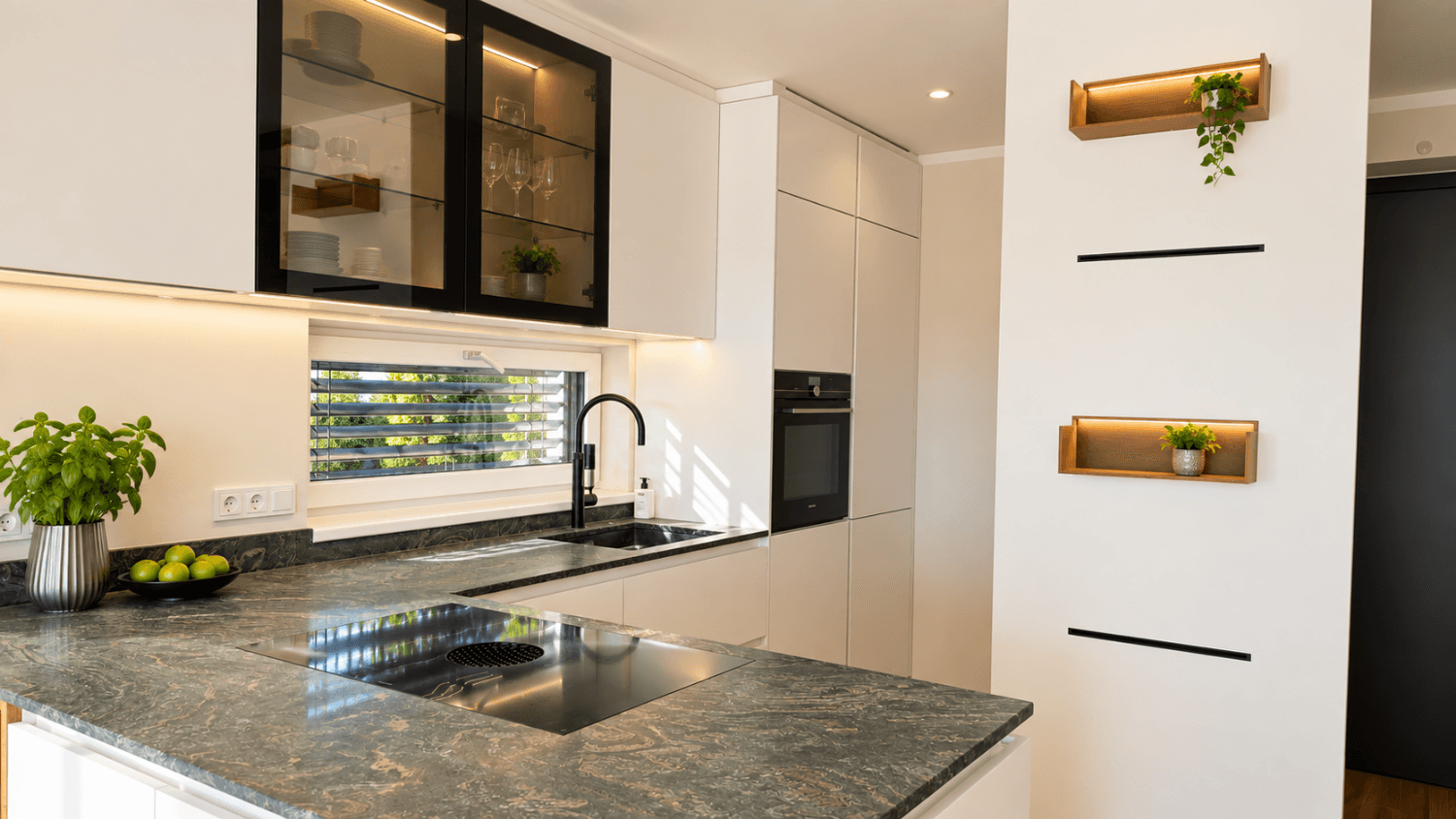 Moderne Küche mit dunkler Granitarbeitsplatte, Induktionskochfeld und integrierten Geräten.