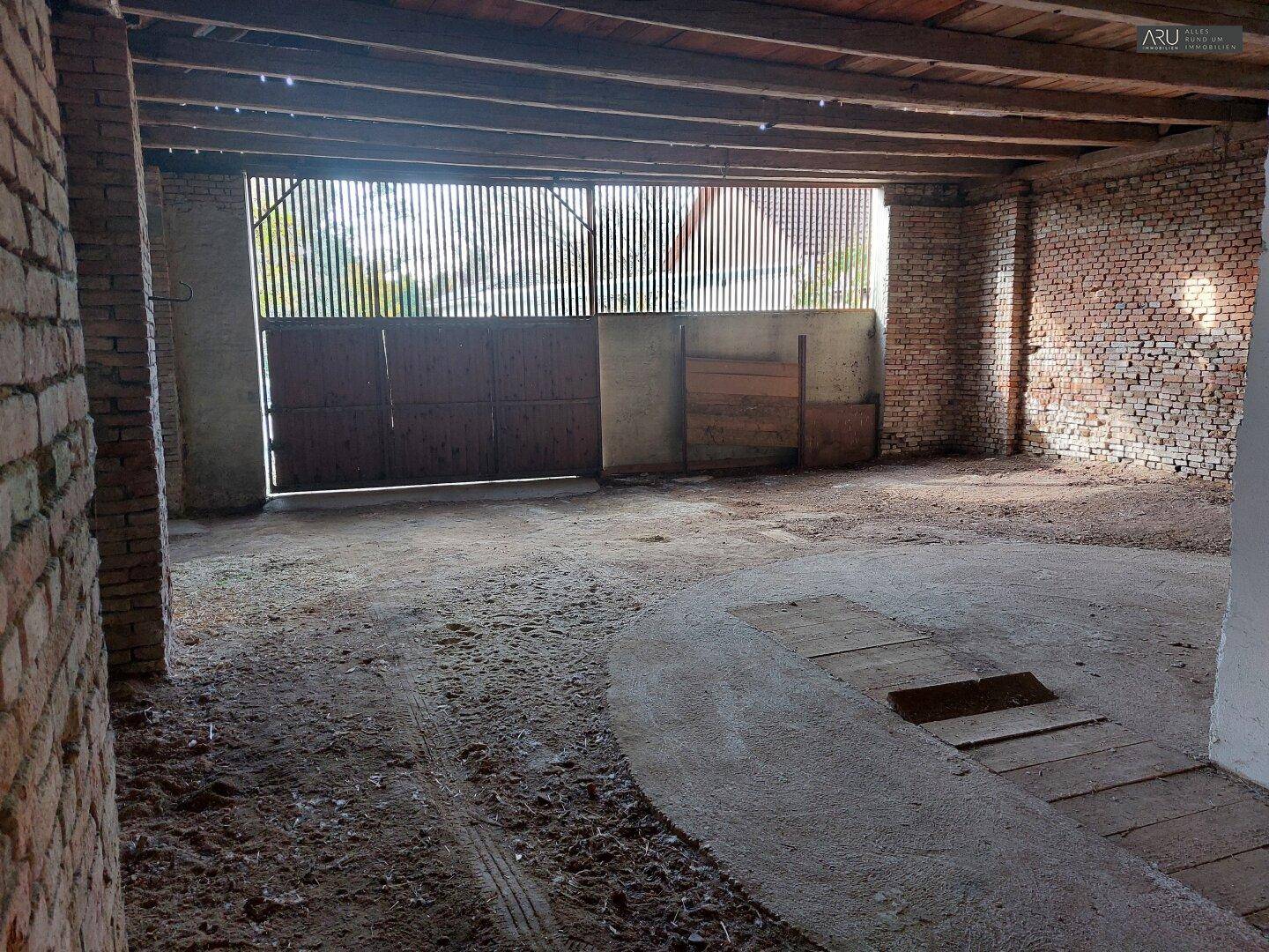 Großer, offener Raum mit Holzbalkendecke und Ziegelwänden, möglicherweise eine Scheune oder Garage.