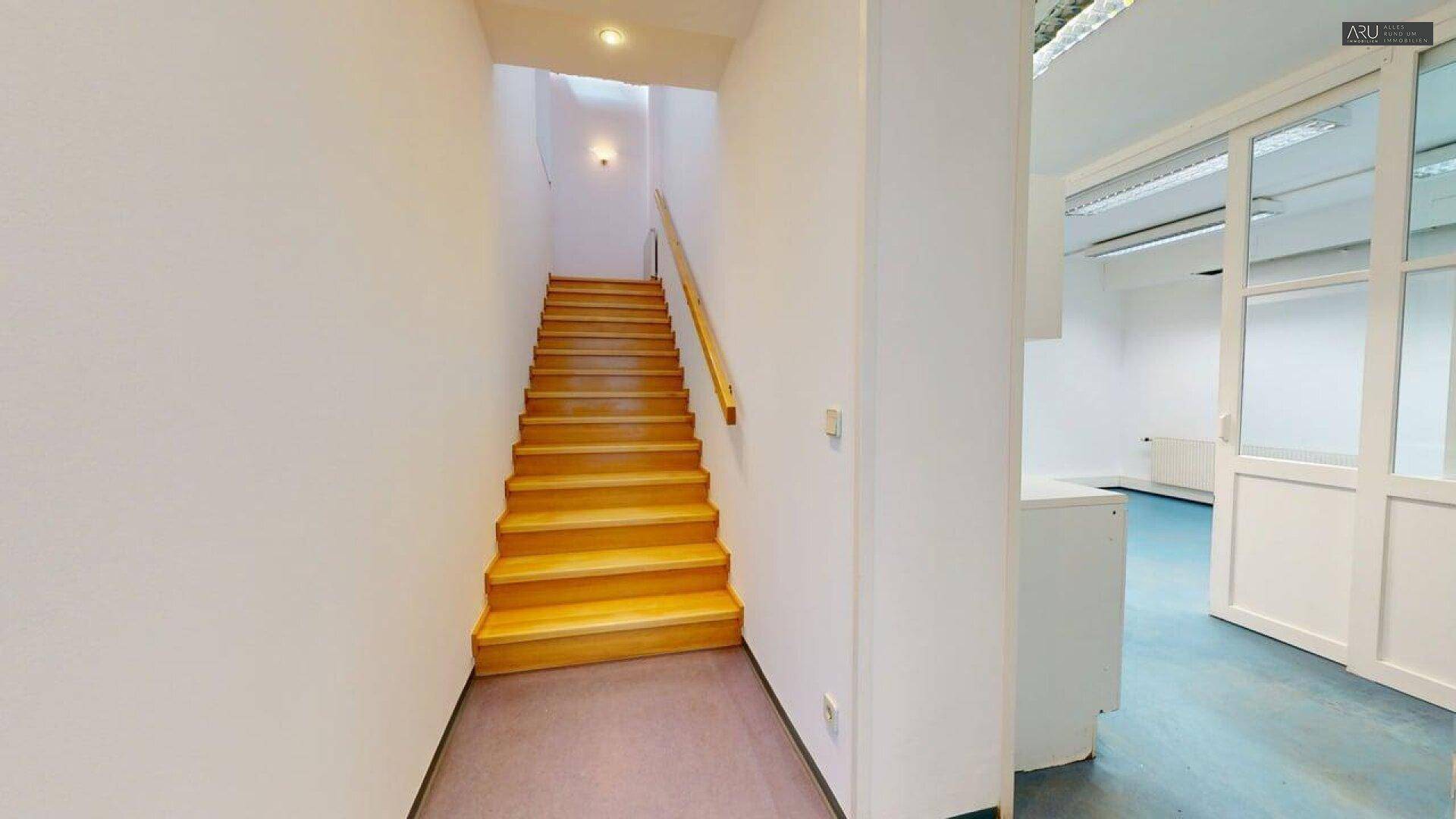 Treppenhaus mit Holzstufen und weiß gestrichenen Wänden, das zu den oberen Etagen führt.