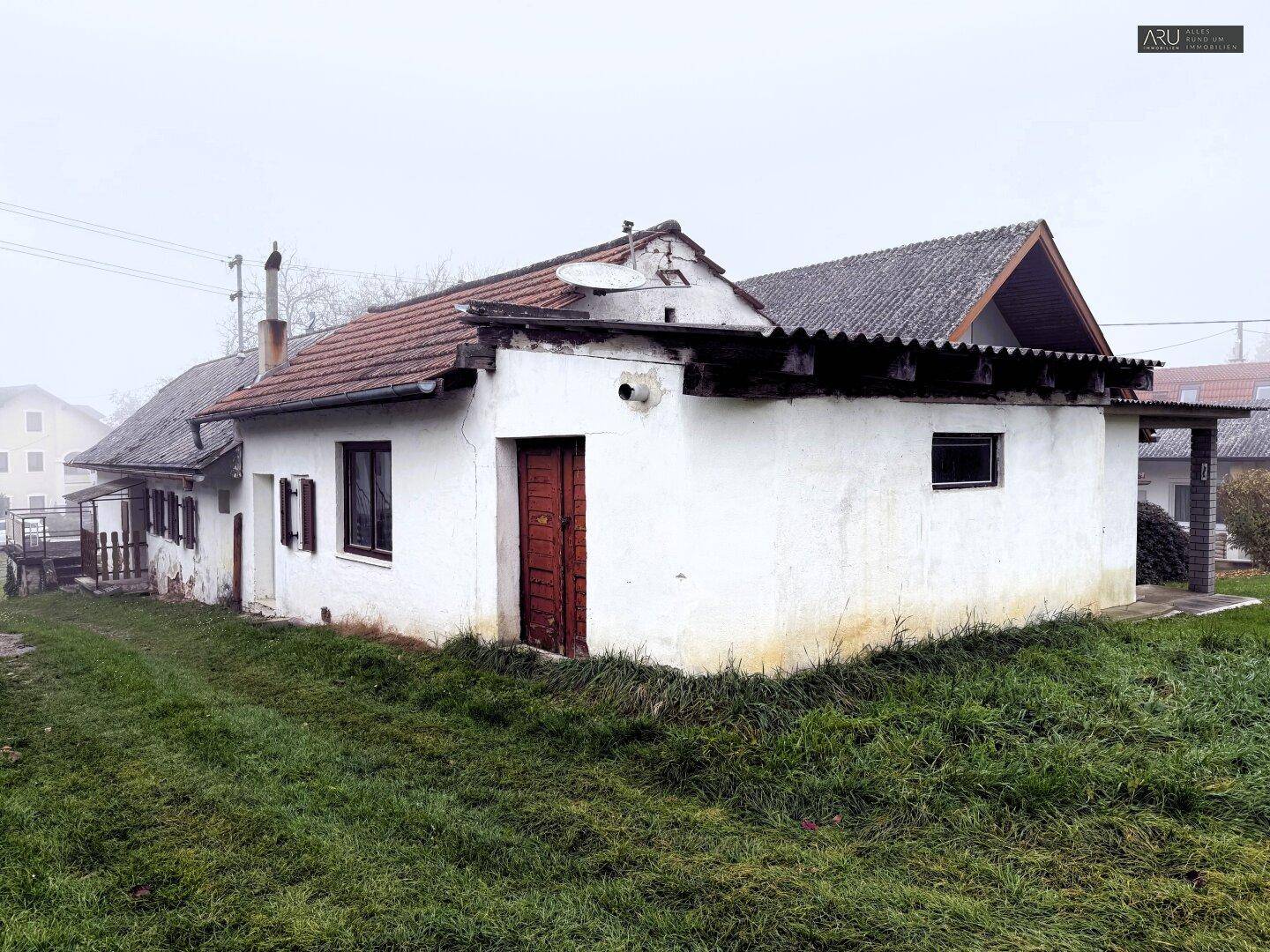 Älteres Wohnhaus mit weißer Fassade, Satteldach und einer Rasenfläche im Vordergrund.