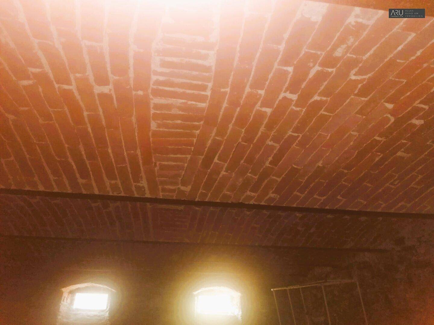 Gewölbte Ziegeldecke in einem Kellerraum mit kleinen Fenstern.