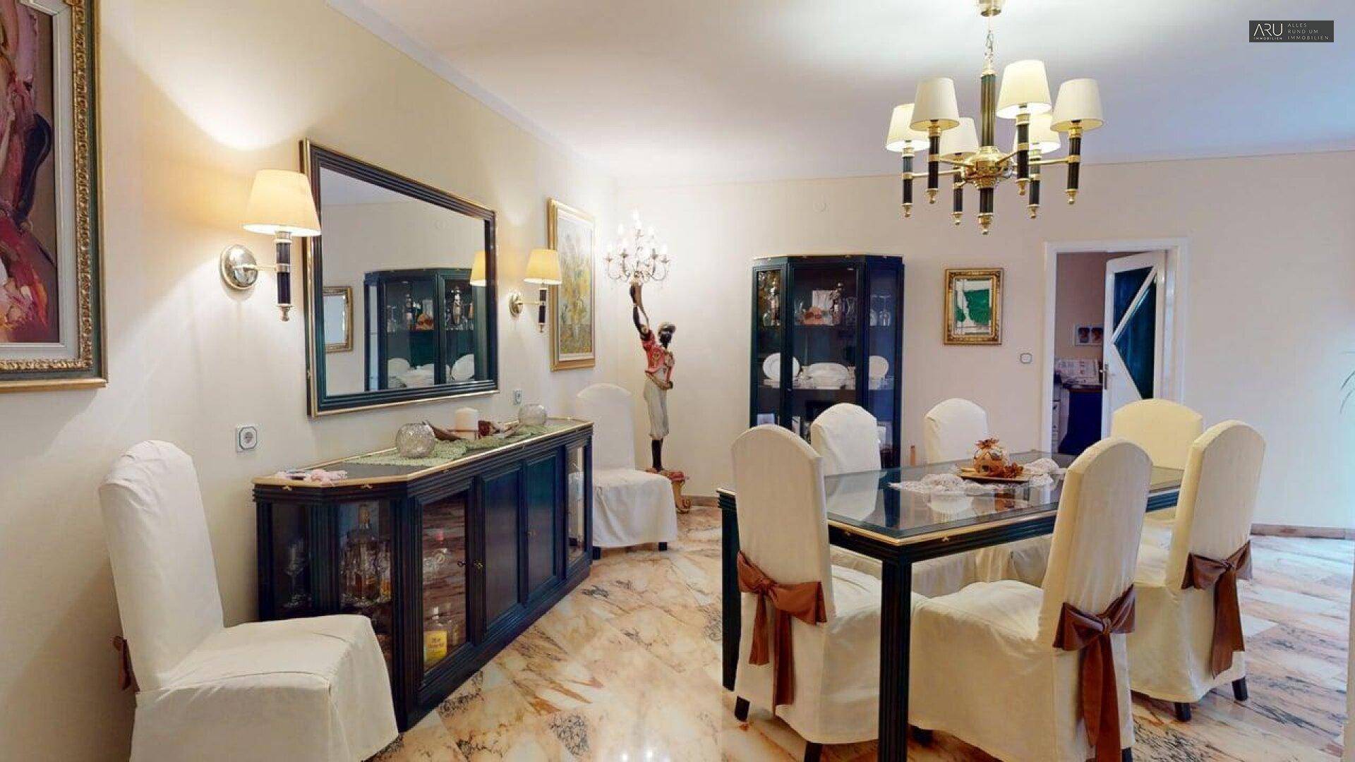Klassischer Essbereich mit großem Tisch, Marmorboden und elegantem Sideboard.