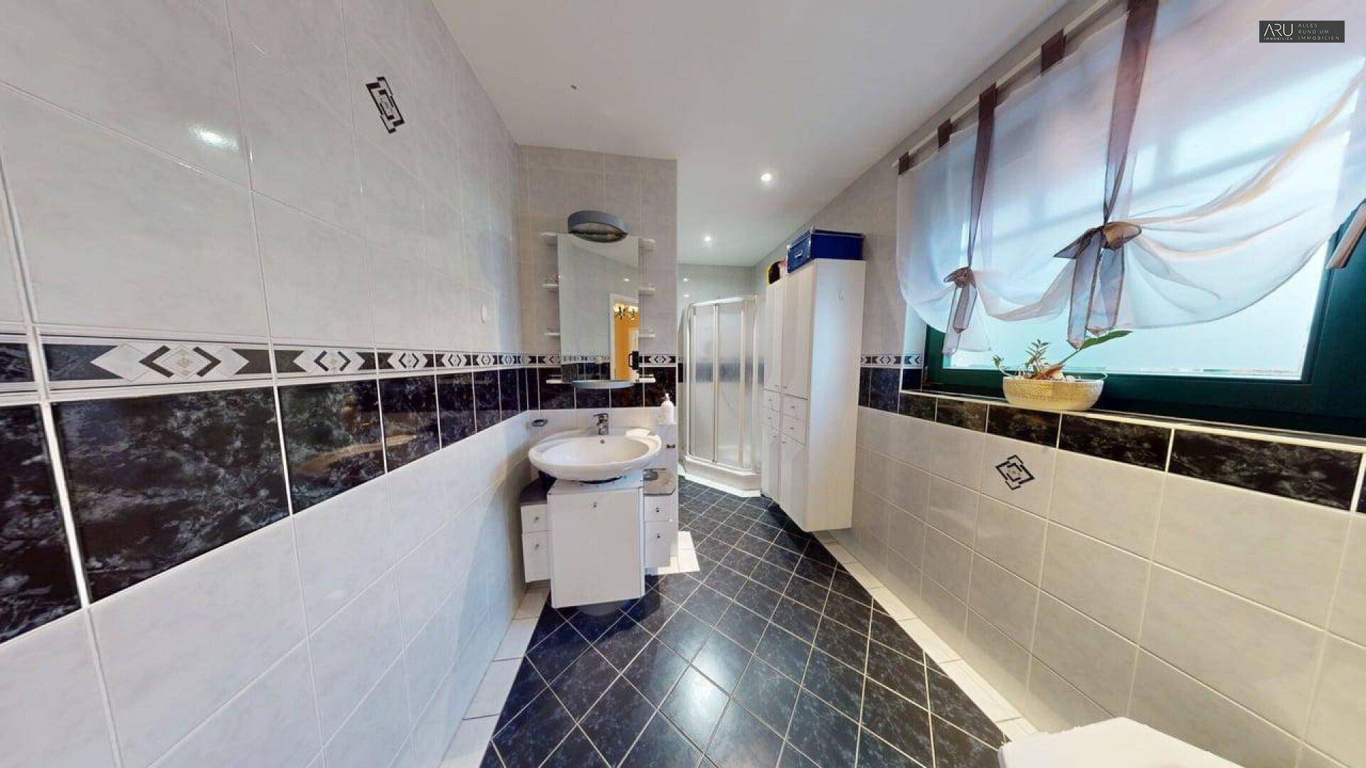 Helles Badezimmer mit Dusche, modernem Waschbecken und Fenster für natürliche Belüftung.