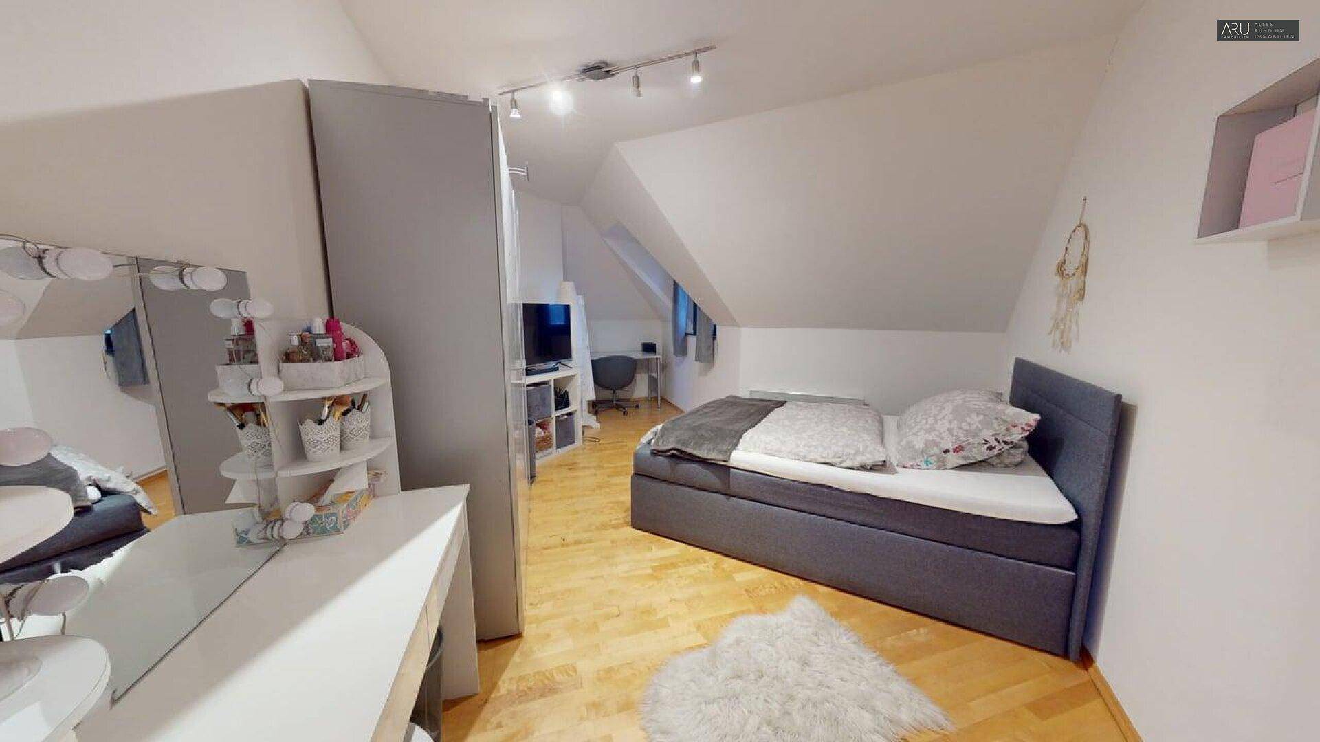 Helles Schlafzimmer im Dachgeschoss mit Holzboden und praktischen Möbeln.
