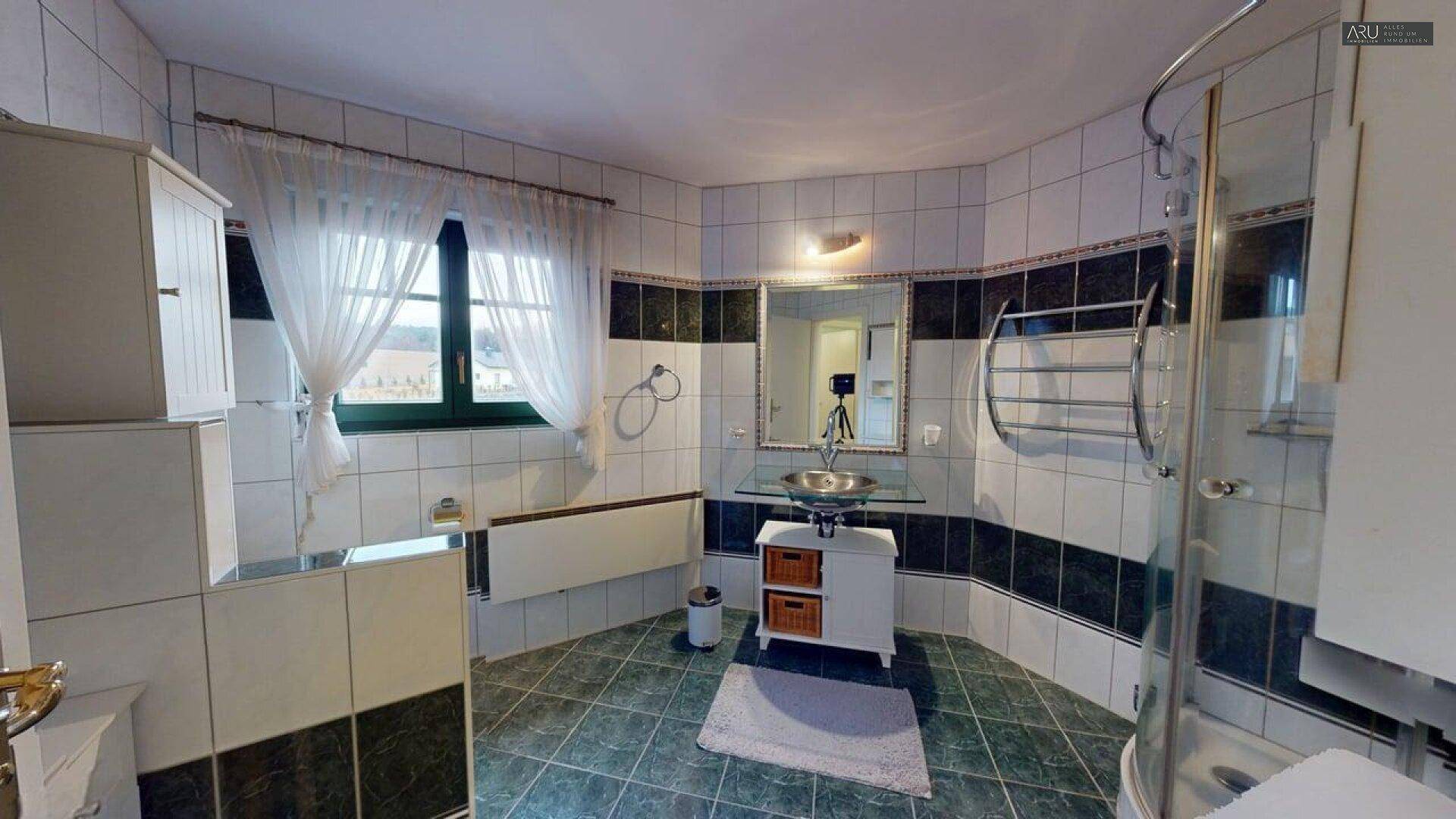 Gefliestes Badezimmer mit Dusche, Waschbecken und Fenster für gute Belüftung.