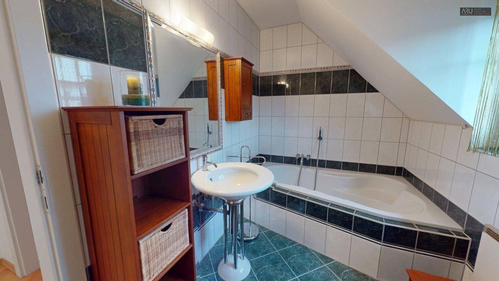 Badezimmer im Dachgeschoss mit Badewanne, Waschbecken und Holzelementen.
