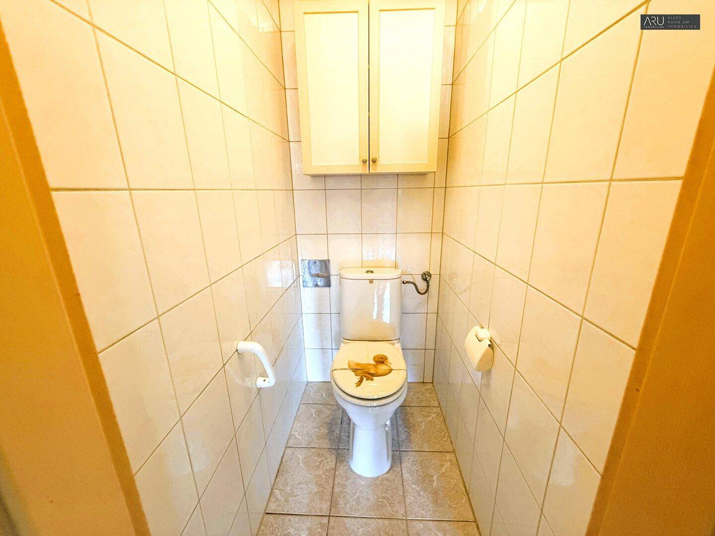 Separate Toilette mit hellen Fliesen und Wand-WC, funktional und sauber.