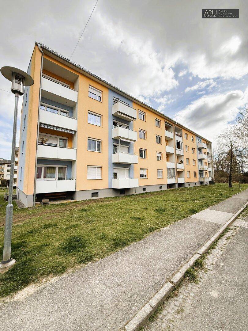Mehrfamilienhaus mit orange-blauer Fassade und mehreren Balkonen.