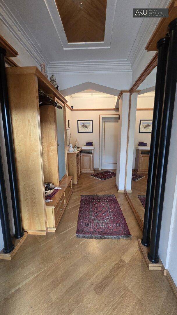 Eingangsbereich mit Holzschrank, Spiegeln und einem Teppich auf dem Holzparkettboden.