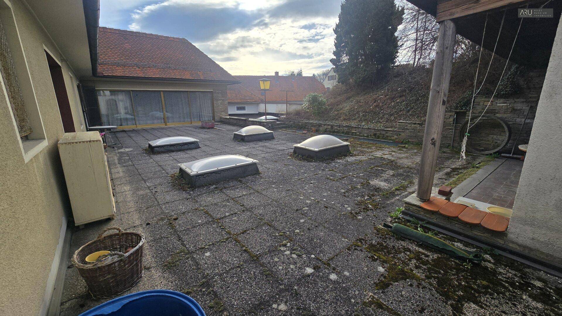 Gepflasterte Terrasse mit mehreren Oberlichtern und Spuren der Witterung, bereit zur Renovierung.