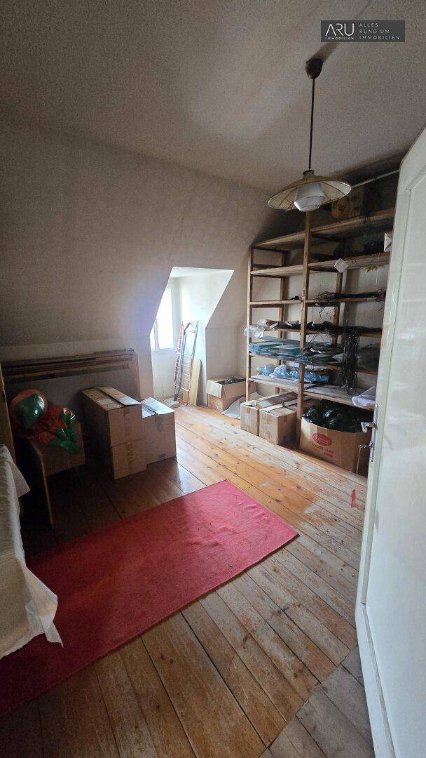 Geräumiger Dachbodenraum mit Holzdielenboden, Dachschrägen und einem Regal für Lagerzwecke.