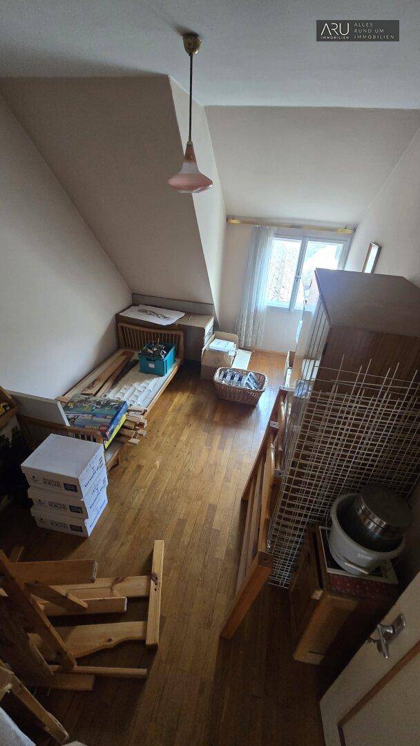 Kleines Schlafzimmer im Dachgeschoss mit Holzboden, Dachschrägen und einem Fenster für Tageslicht.